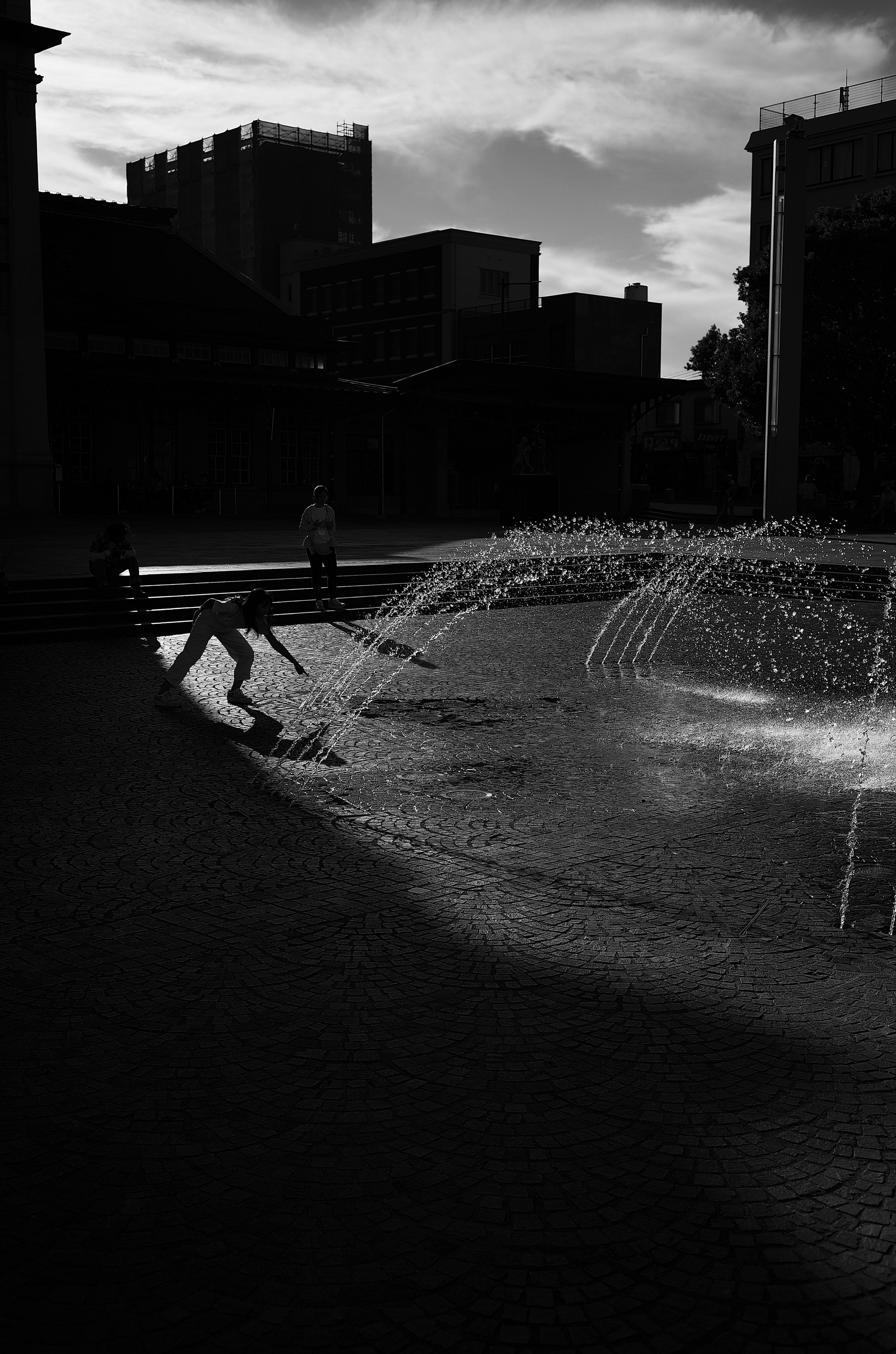 Silhouette d'une personne travaillant près d'une fontaine en contraste noir et blanc