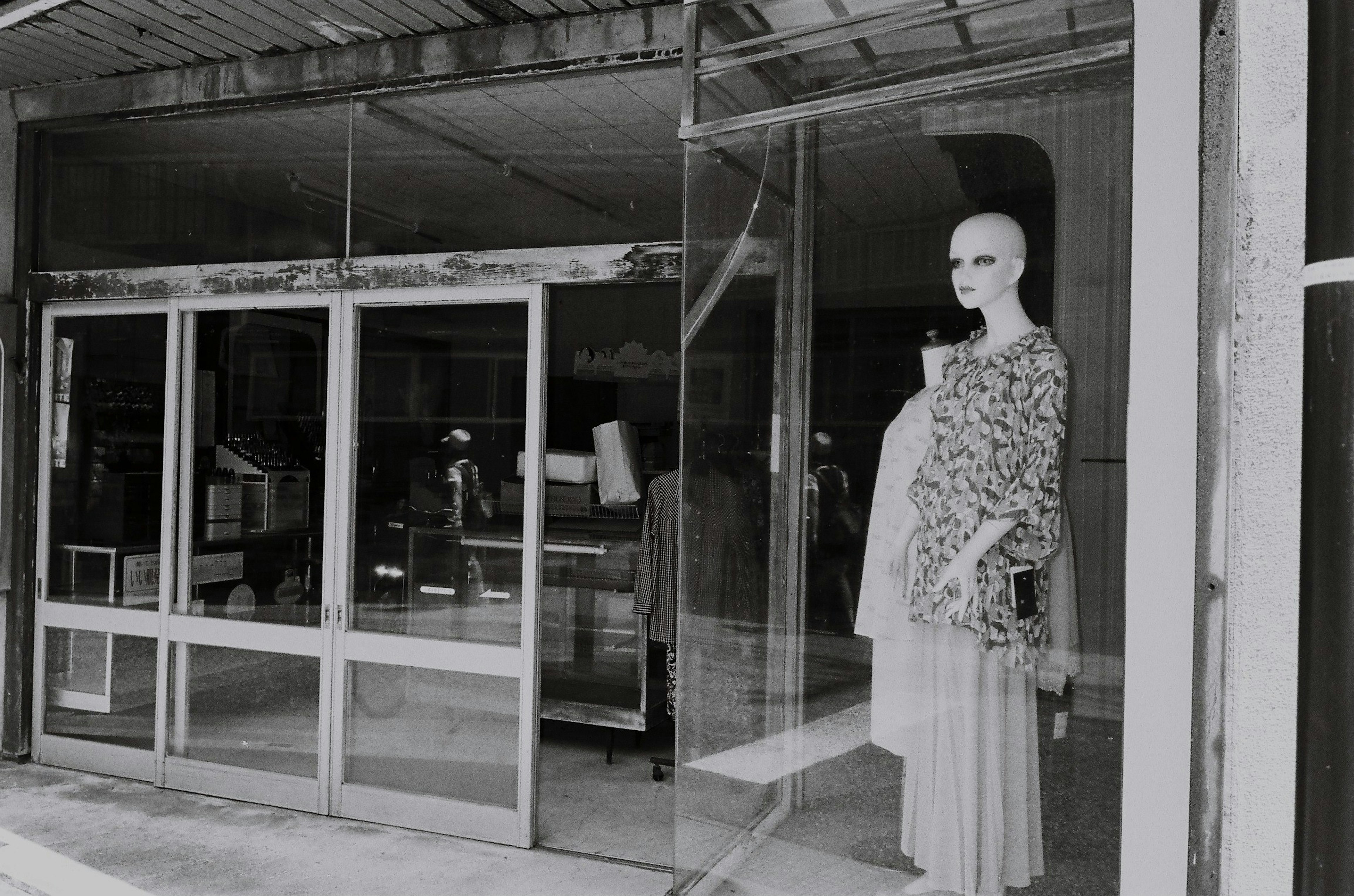 Vue extérieure d'un magasin avec un mannequin et des portes en verre