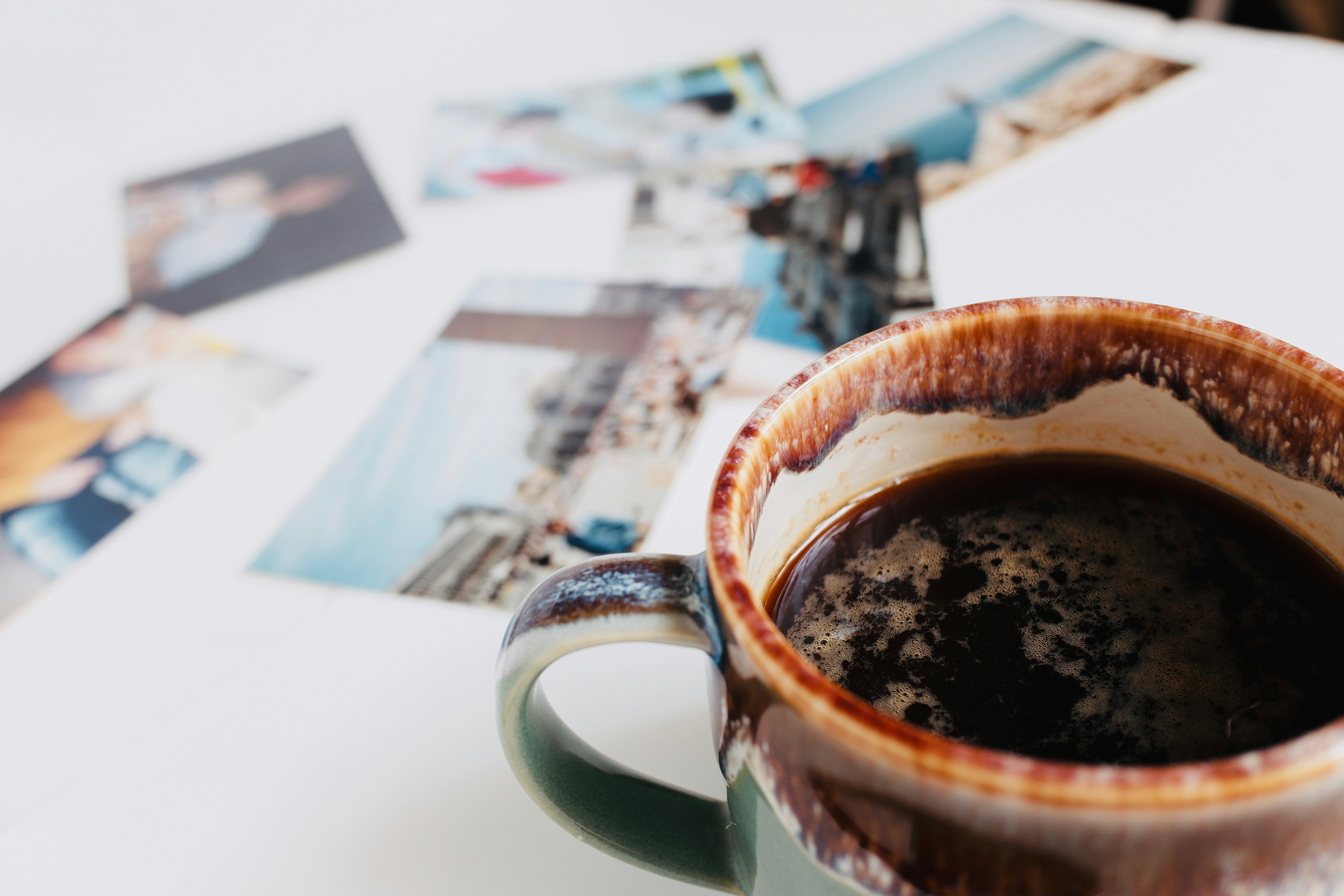 Kaffeetasse mit verstreuten Fotografien auf einem Tisch