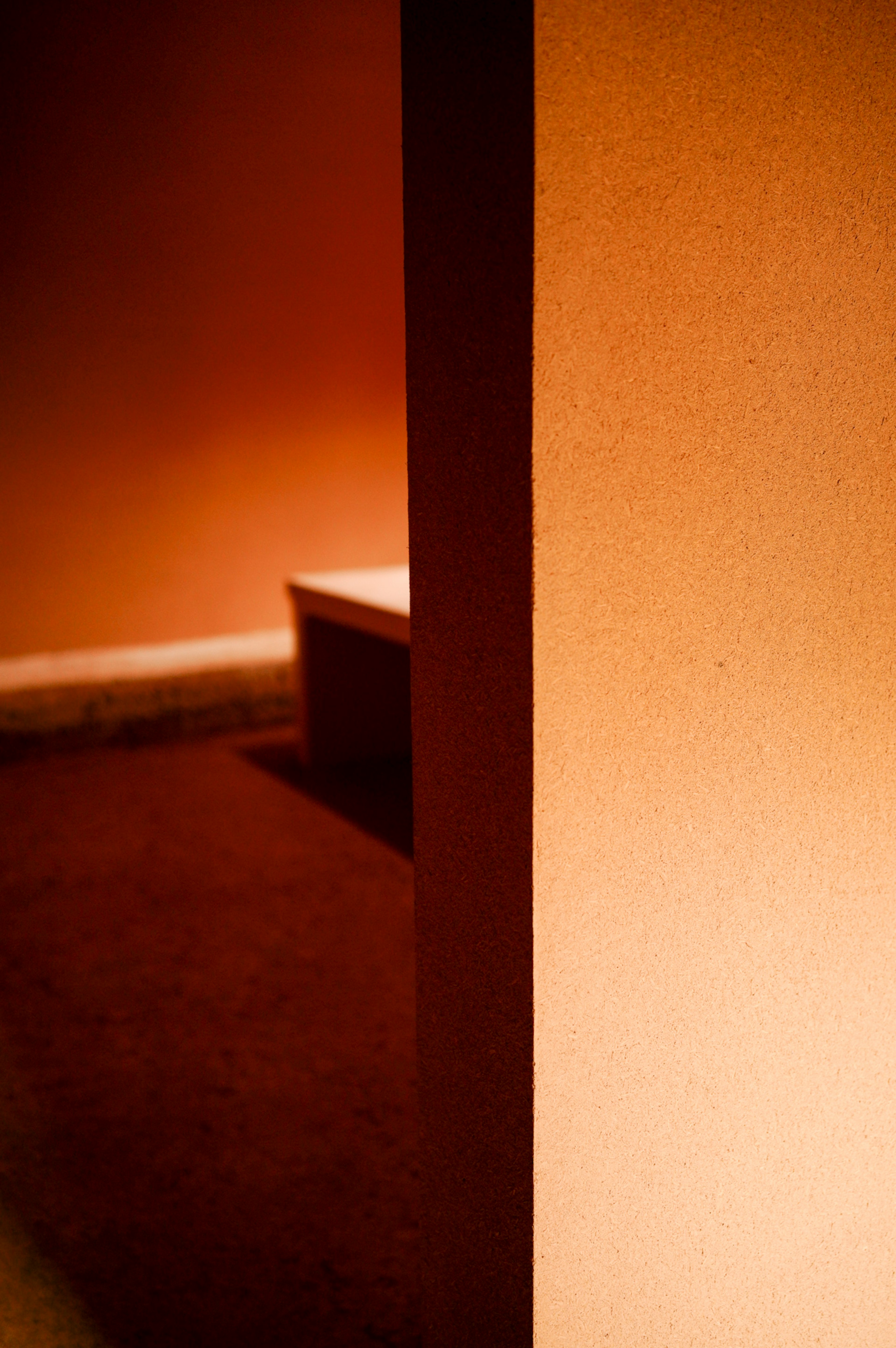 Corner of a softly lit room with warm orange walls and floor