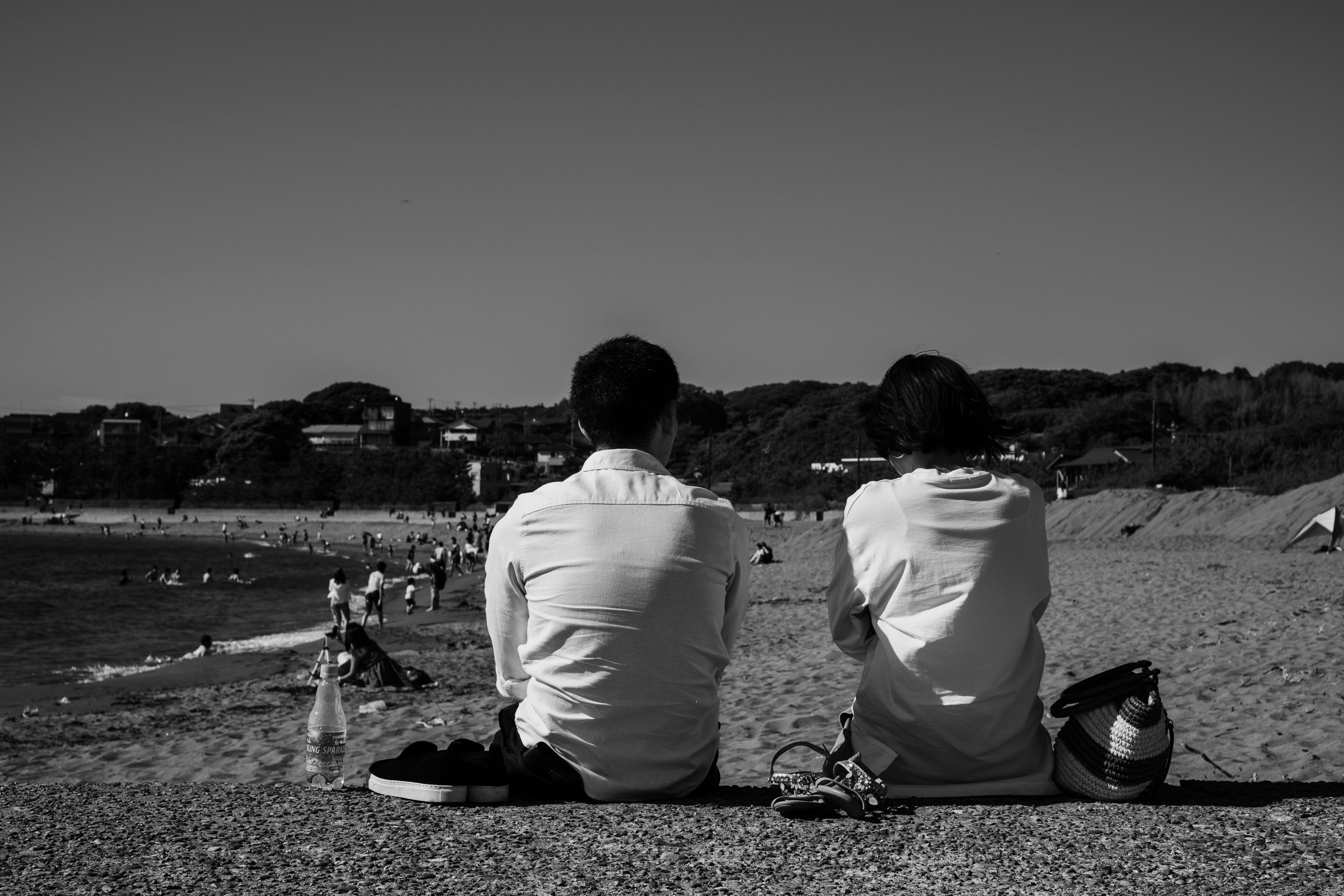 Zwei Personen sitzen nebeneinander am Strand