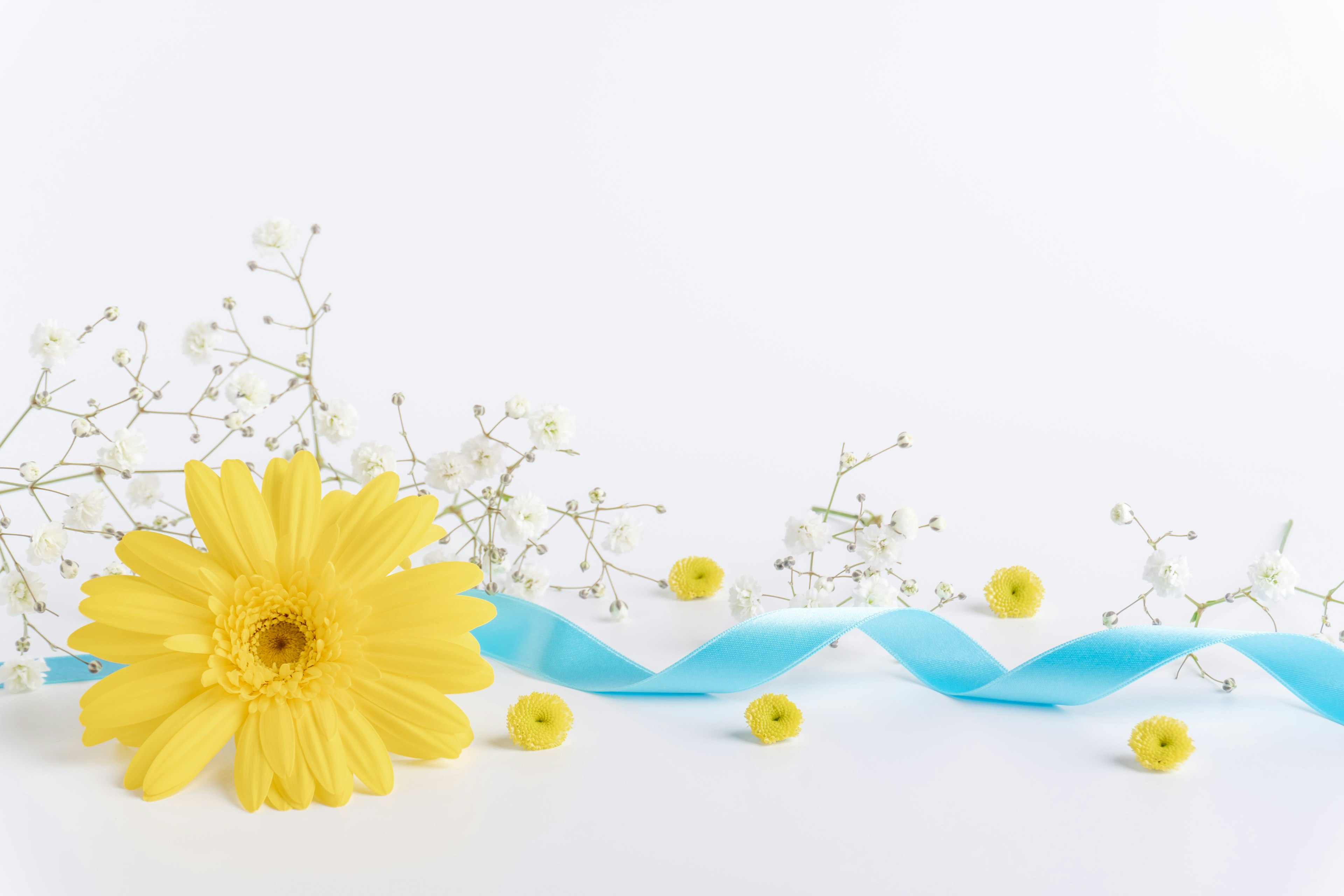 Arrangement of a yellow flower blue ribbon and white small flowers