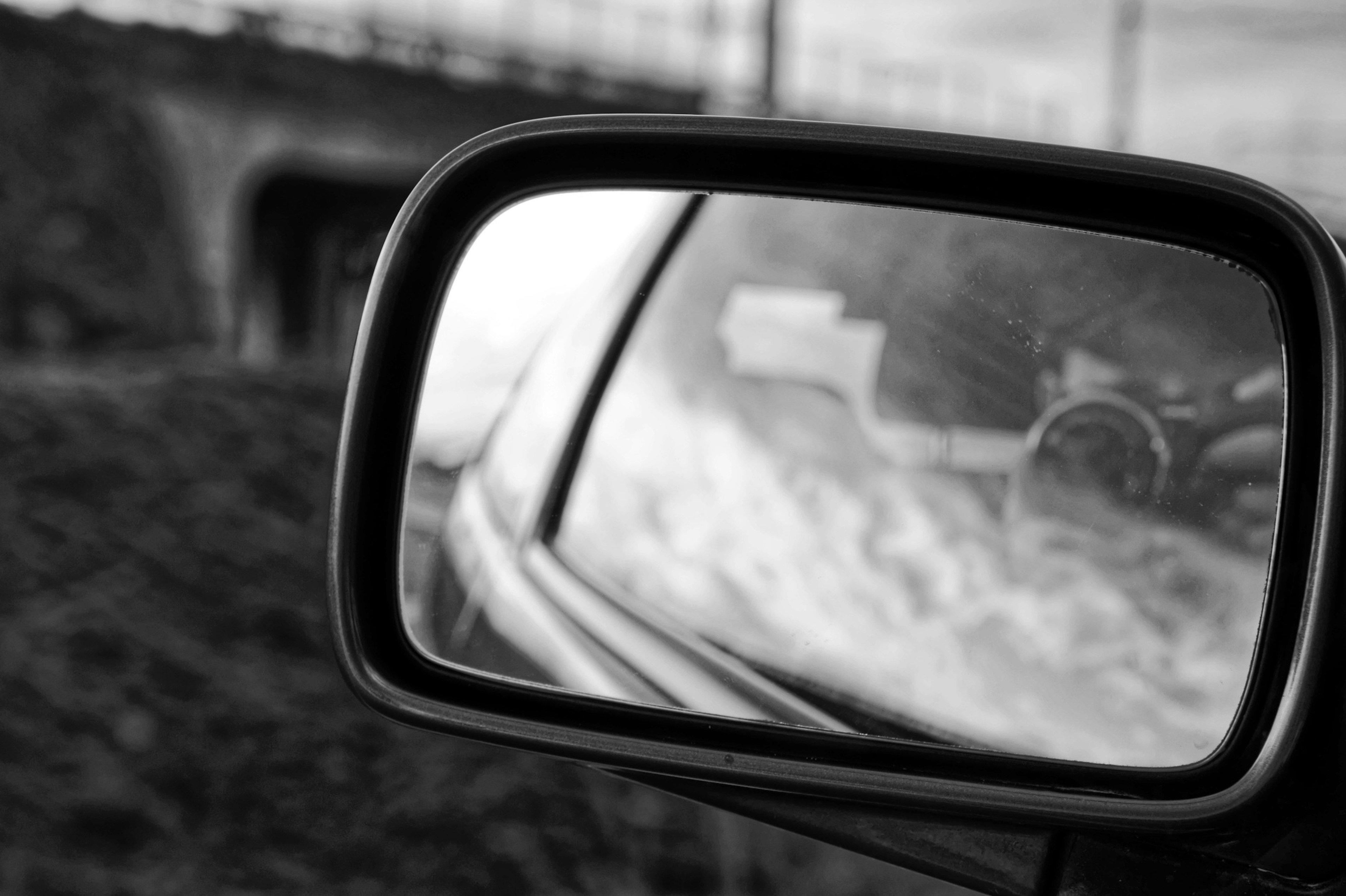 Réflexion en noir et blanc dans le rétroviseur d'une voiture montrant le paysage