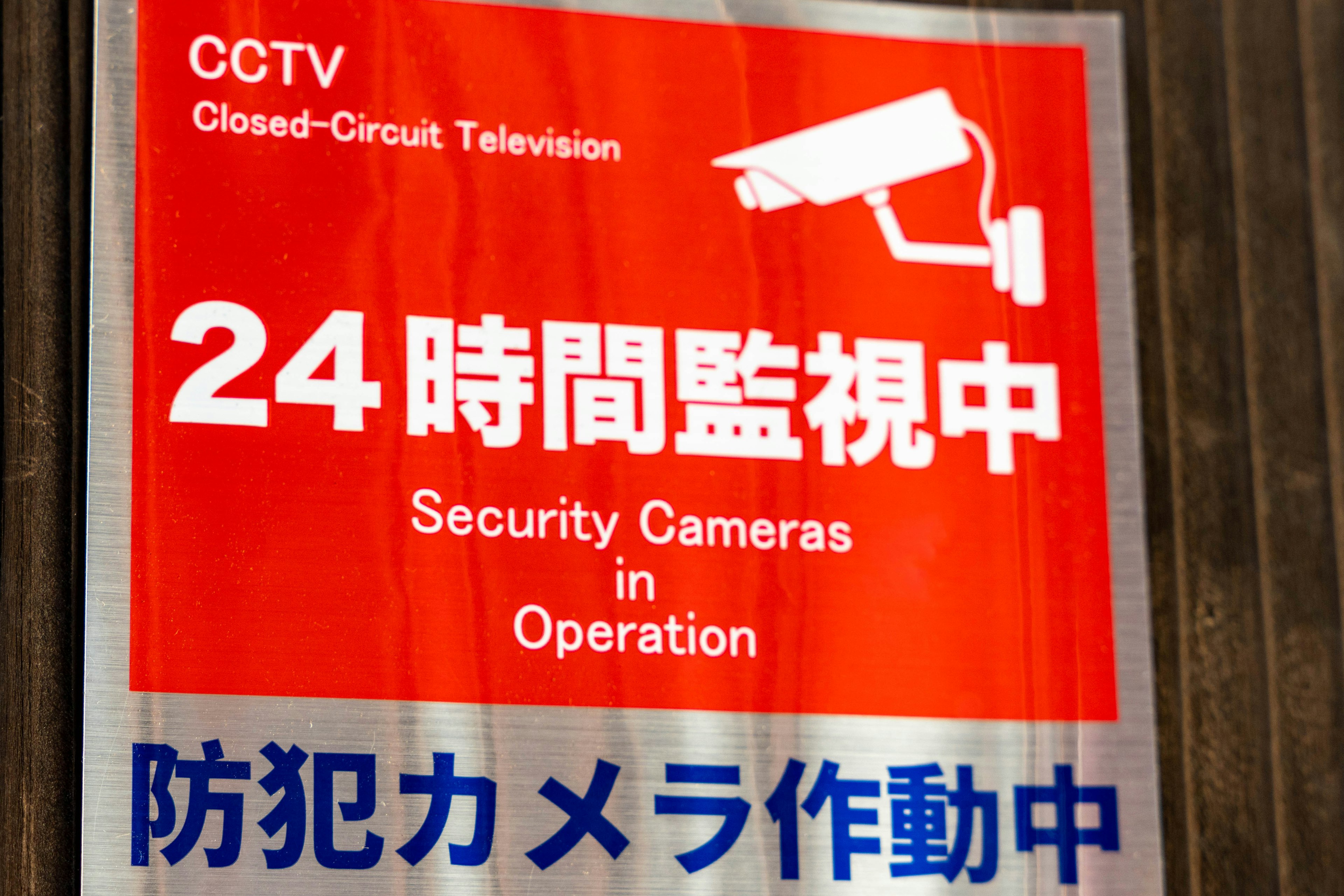 Red sign indicating security camera operation 24 hours monitoring in effect