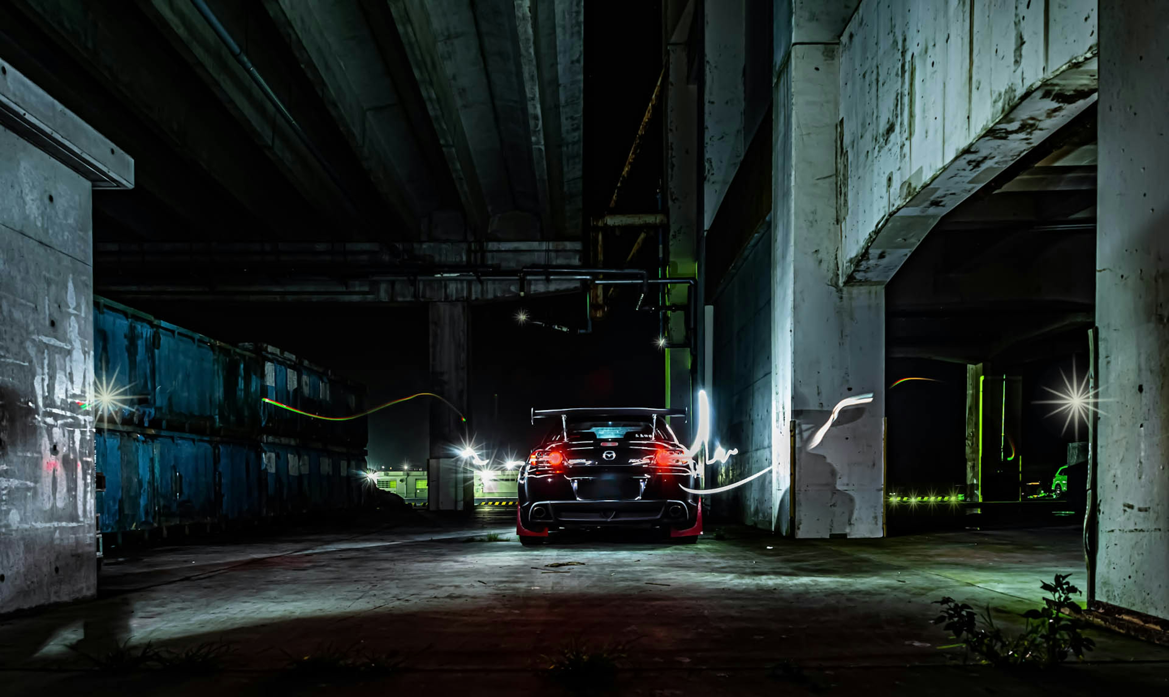 Coche deportivo estacionado en una zona subterránea oscura con estelas de luz coloridas