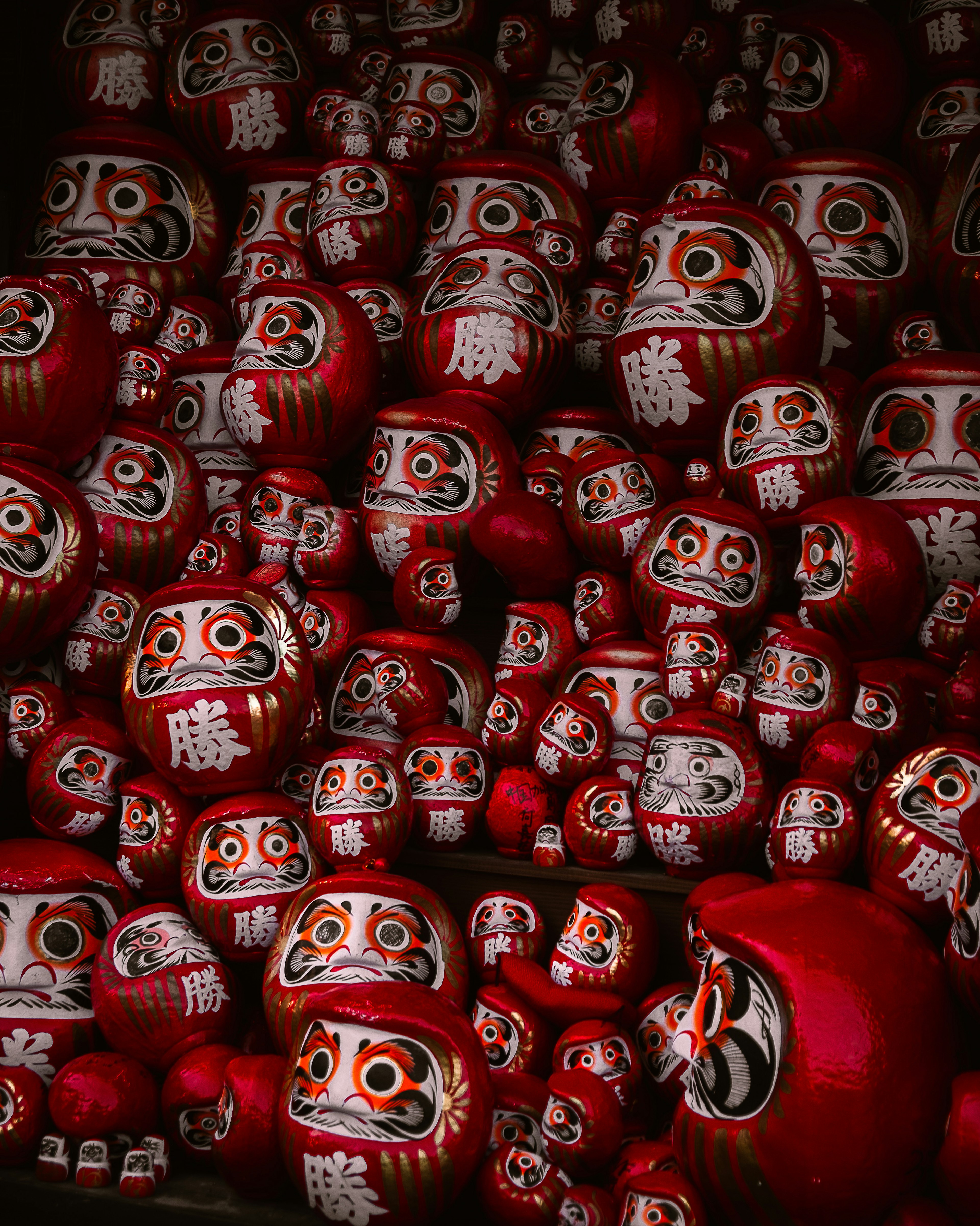 Una colección de muñecas Daruma rojas con rasgos faciales distintivos