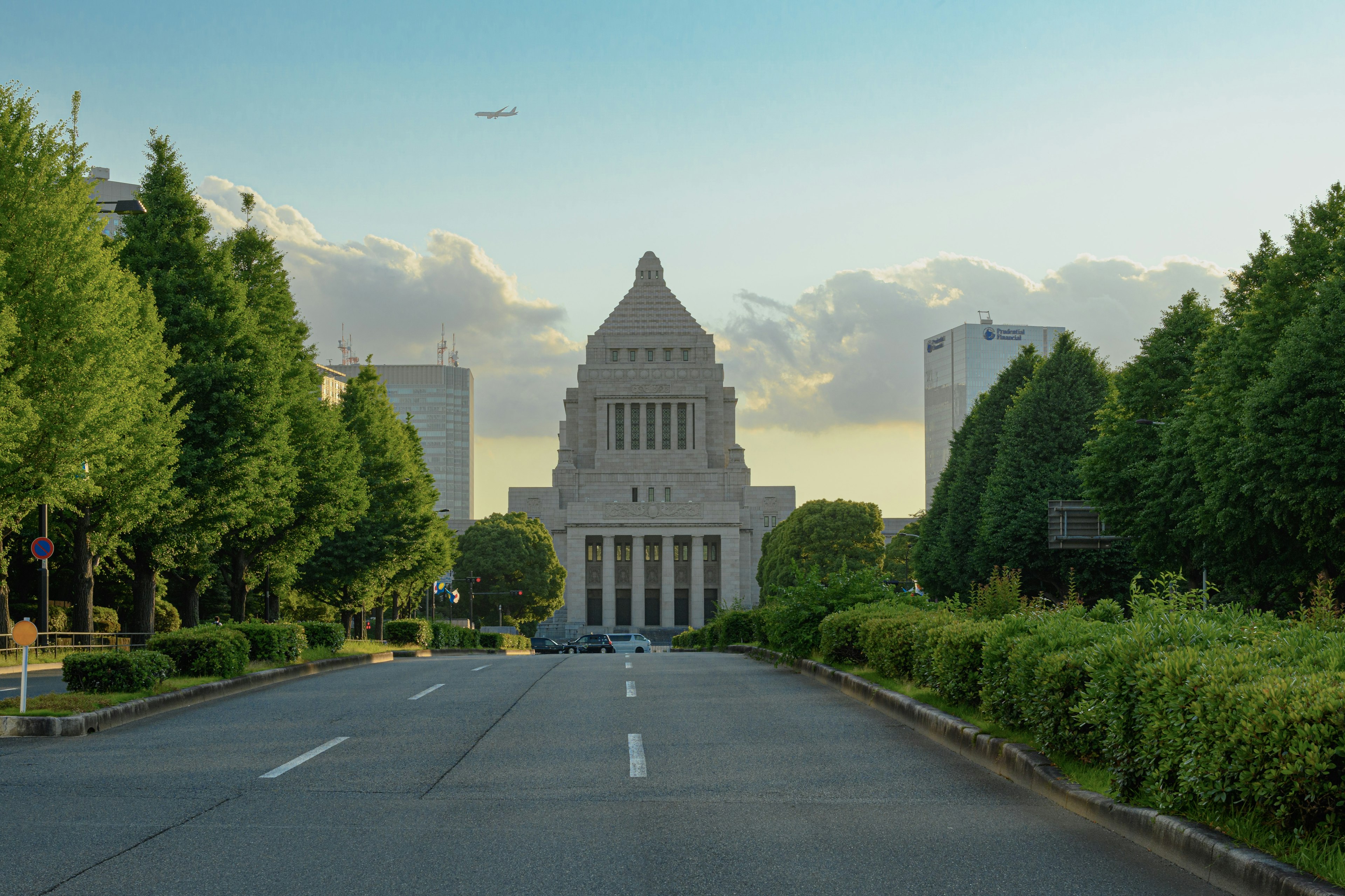 Wide street leading to the National Diet Building with lush trees and blue sky