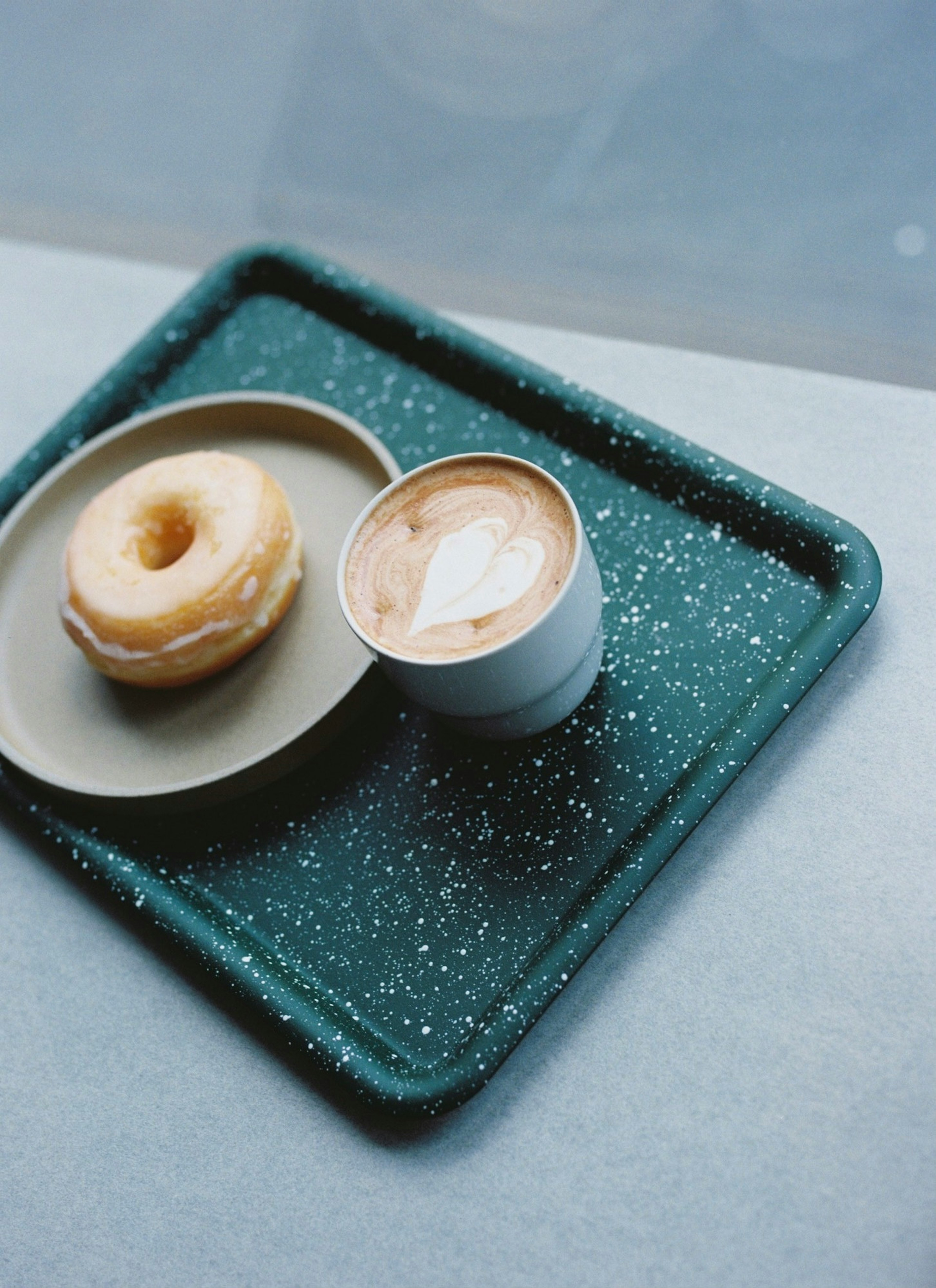 緑のトレイに置かれたドーナツとカフェラテ