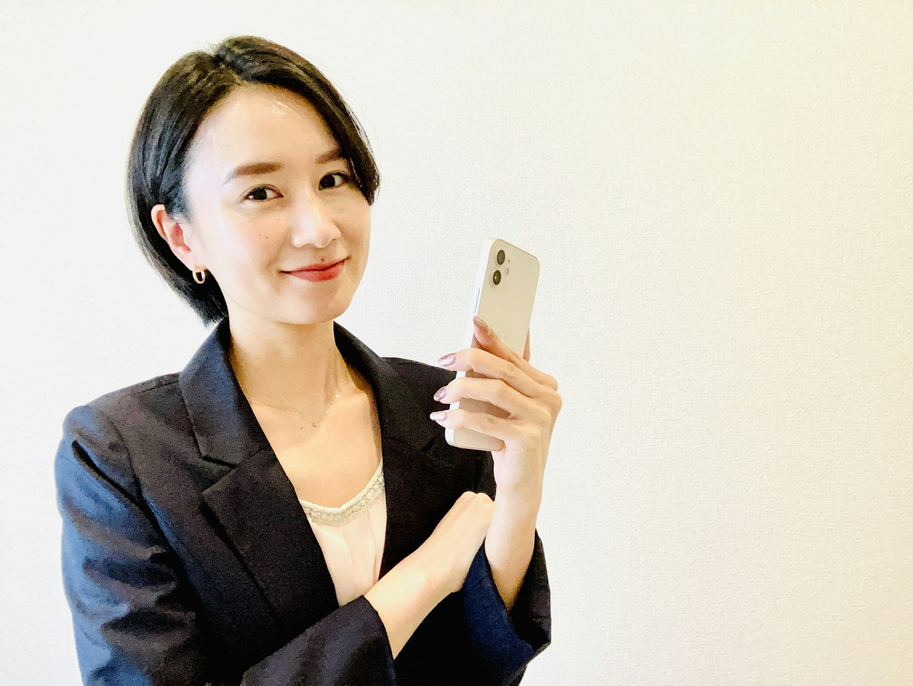 ビジネススーツを着た女性がスマートフォンを持って微笑んでいる