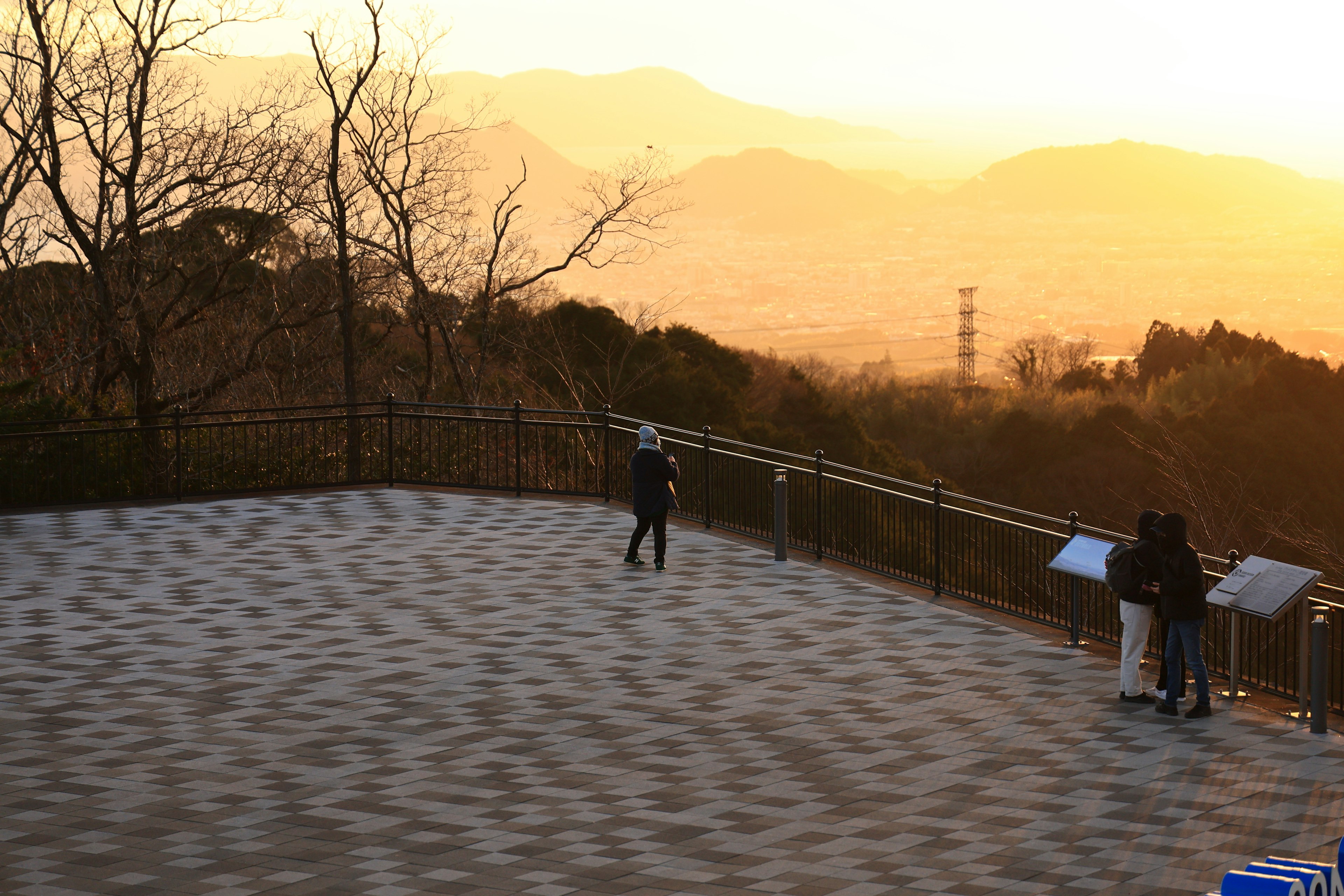 Mirador con atardecer sobre las montañas y visitantes observando