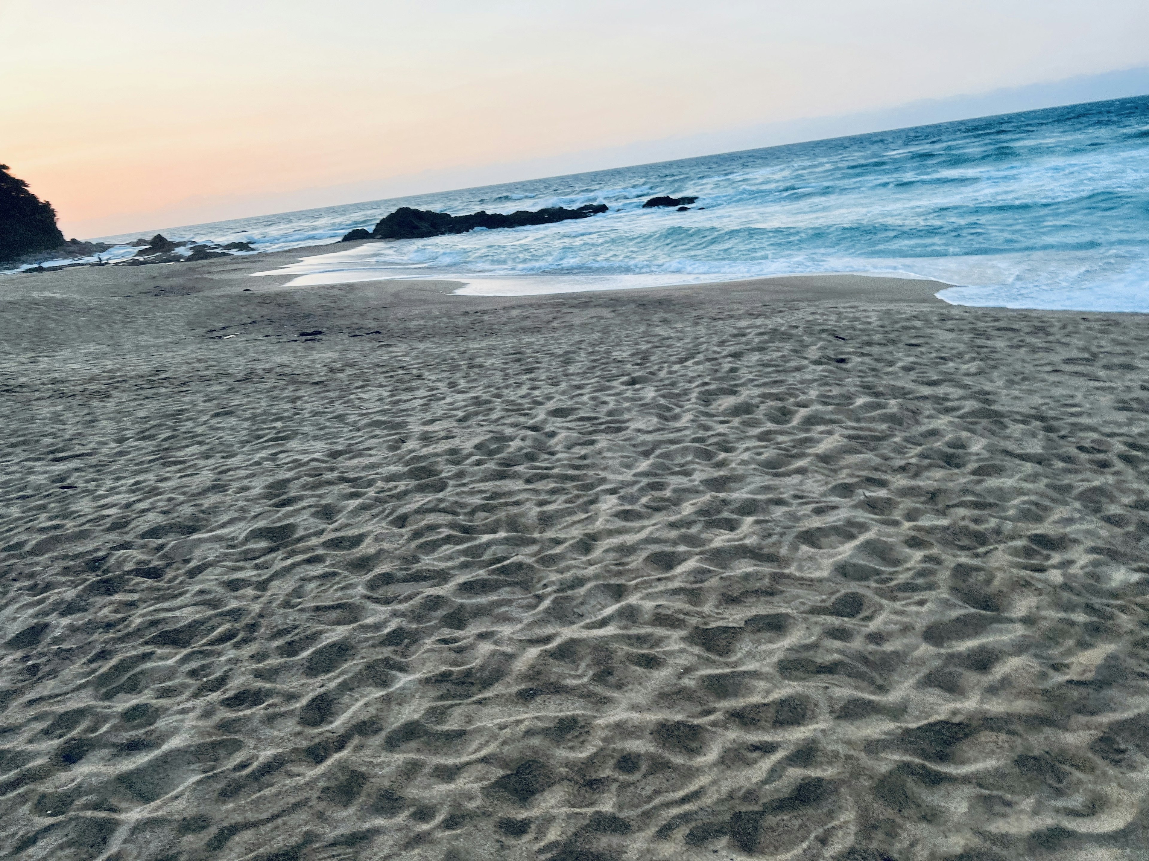 Plage de sable avec des vagues douces et un coucher de soleil serein