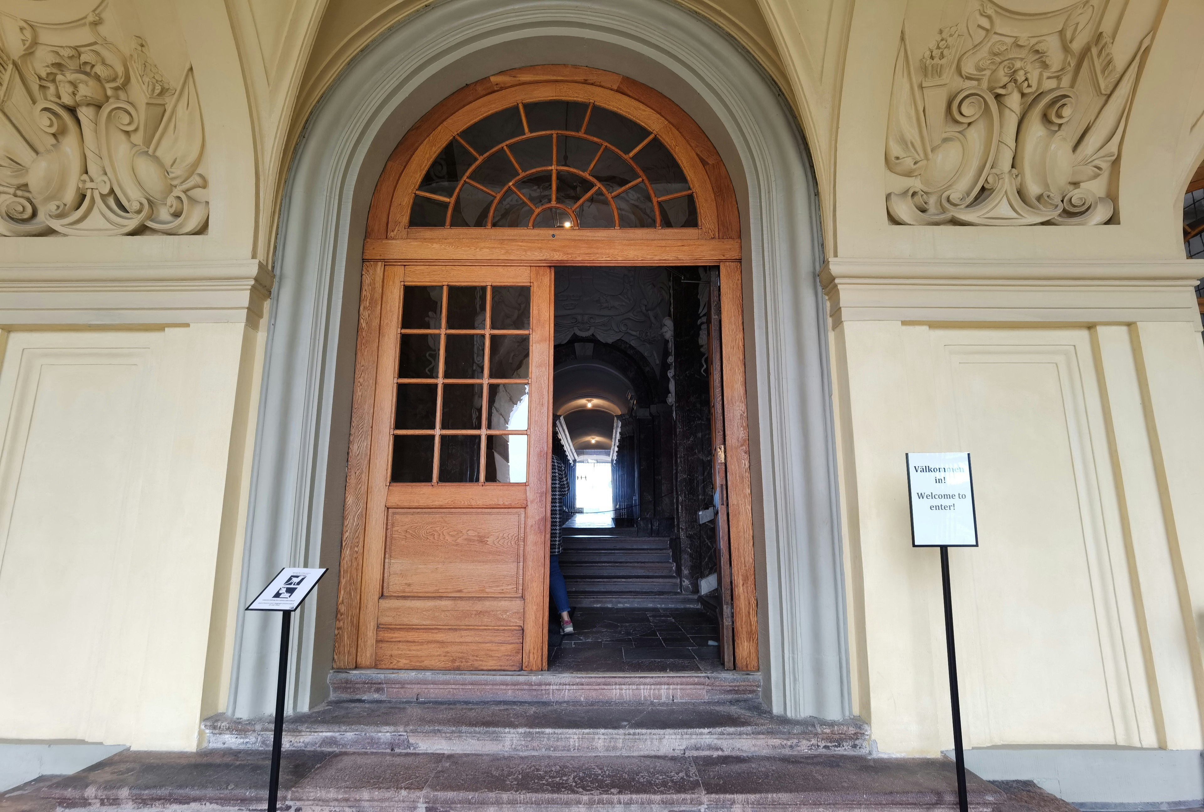 Entrée d'un bâtiment avec une belle porte en bois et des escaliers intérieurs visibles