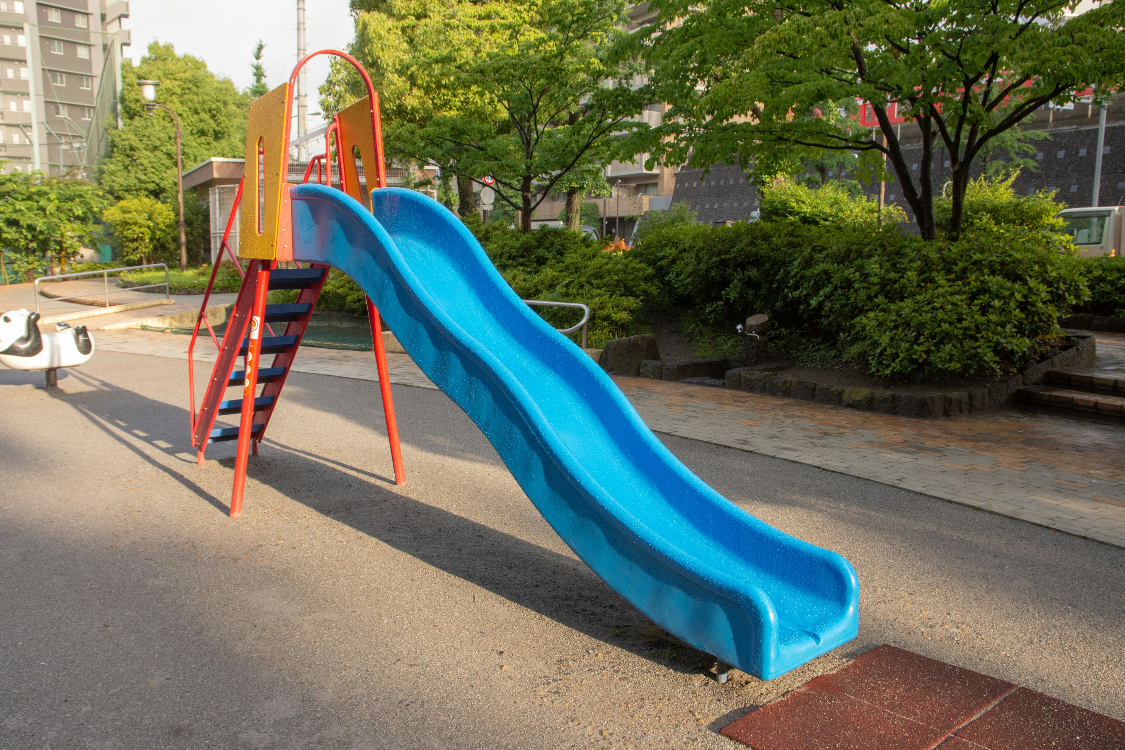 Blue slide with red ladder in a park setting