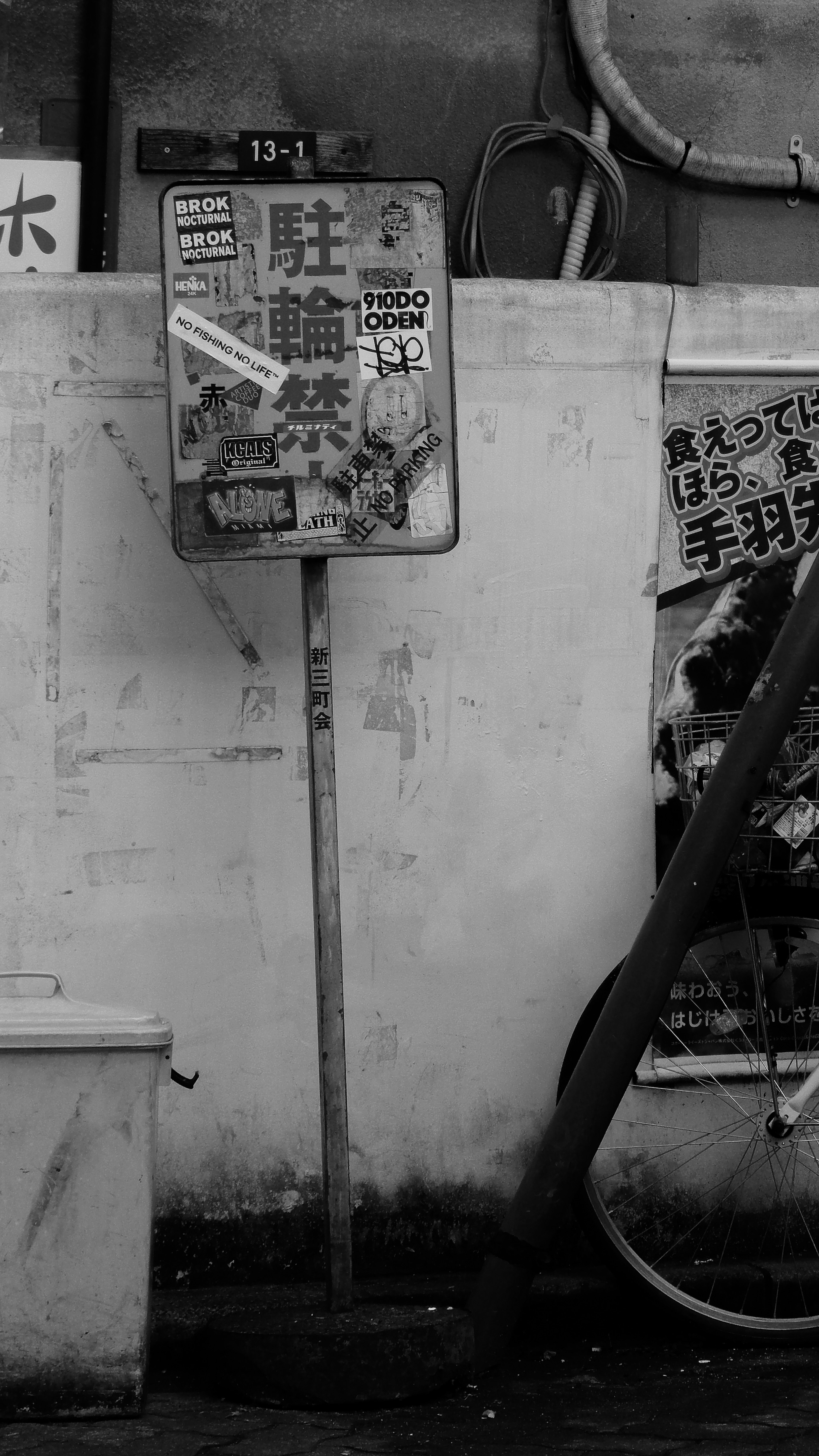 Un viejo letrero de estacionamiento apoyado contra una pared en blanco y negro