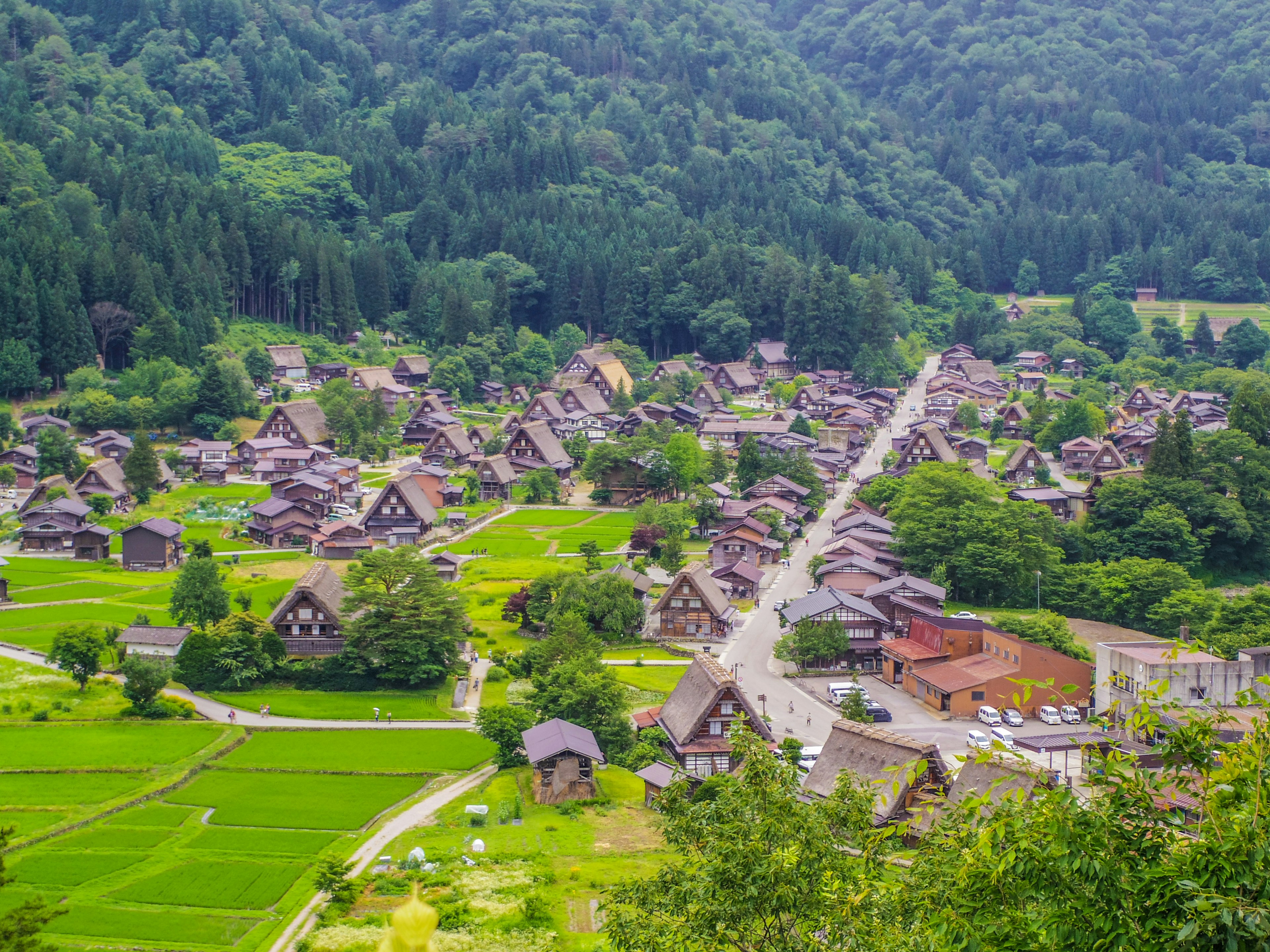 Scenic view of a tranquil village surrounded by mountains traditional gassho-style houses scattered throughout