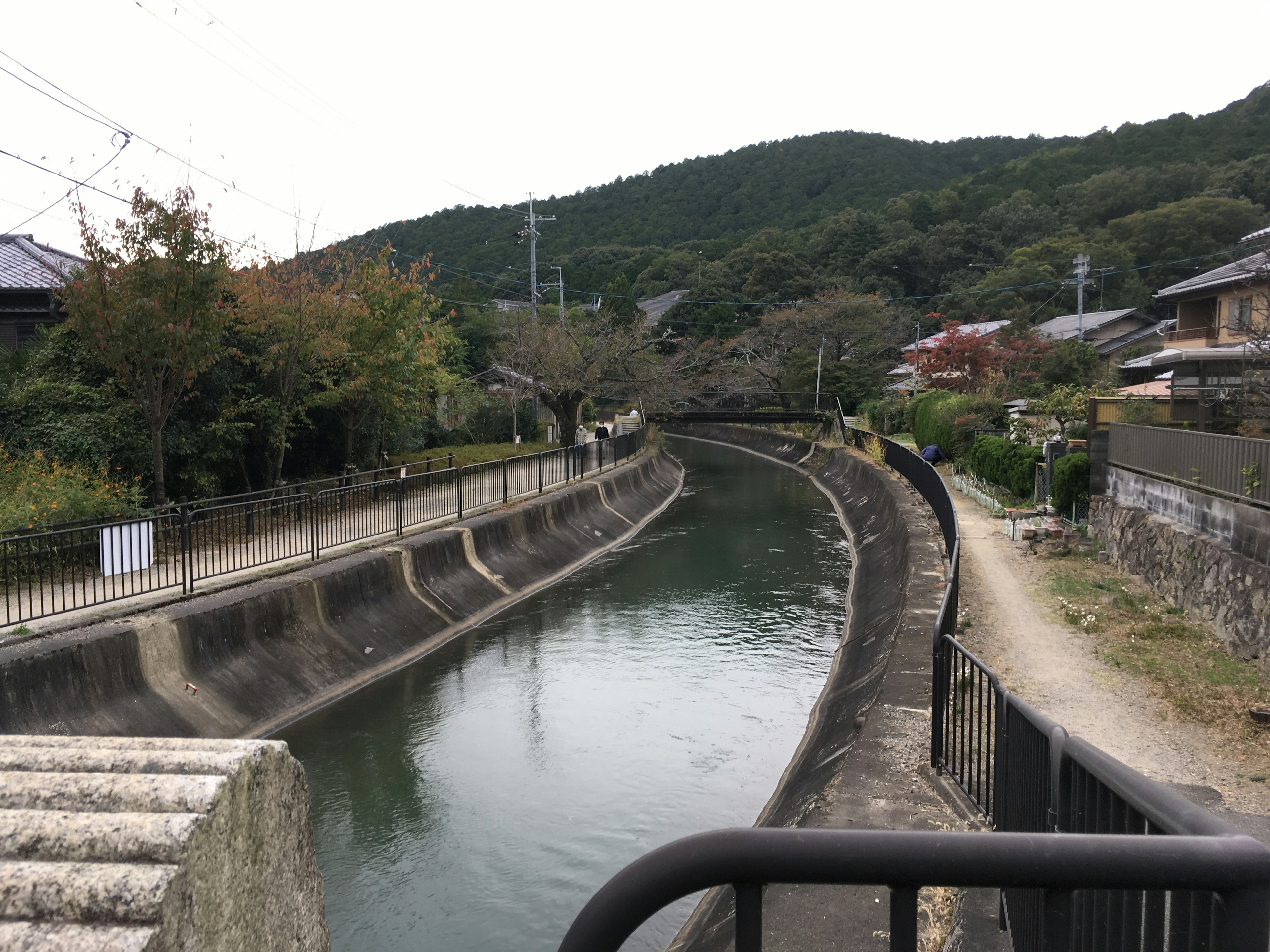 Río tranquilo con área residencial circundante Vegetación natural y montañas al fondo