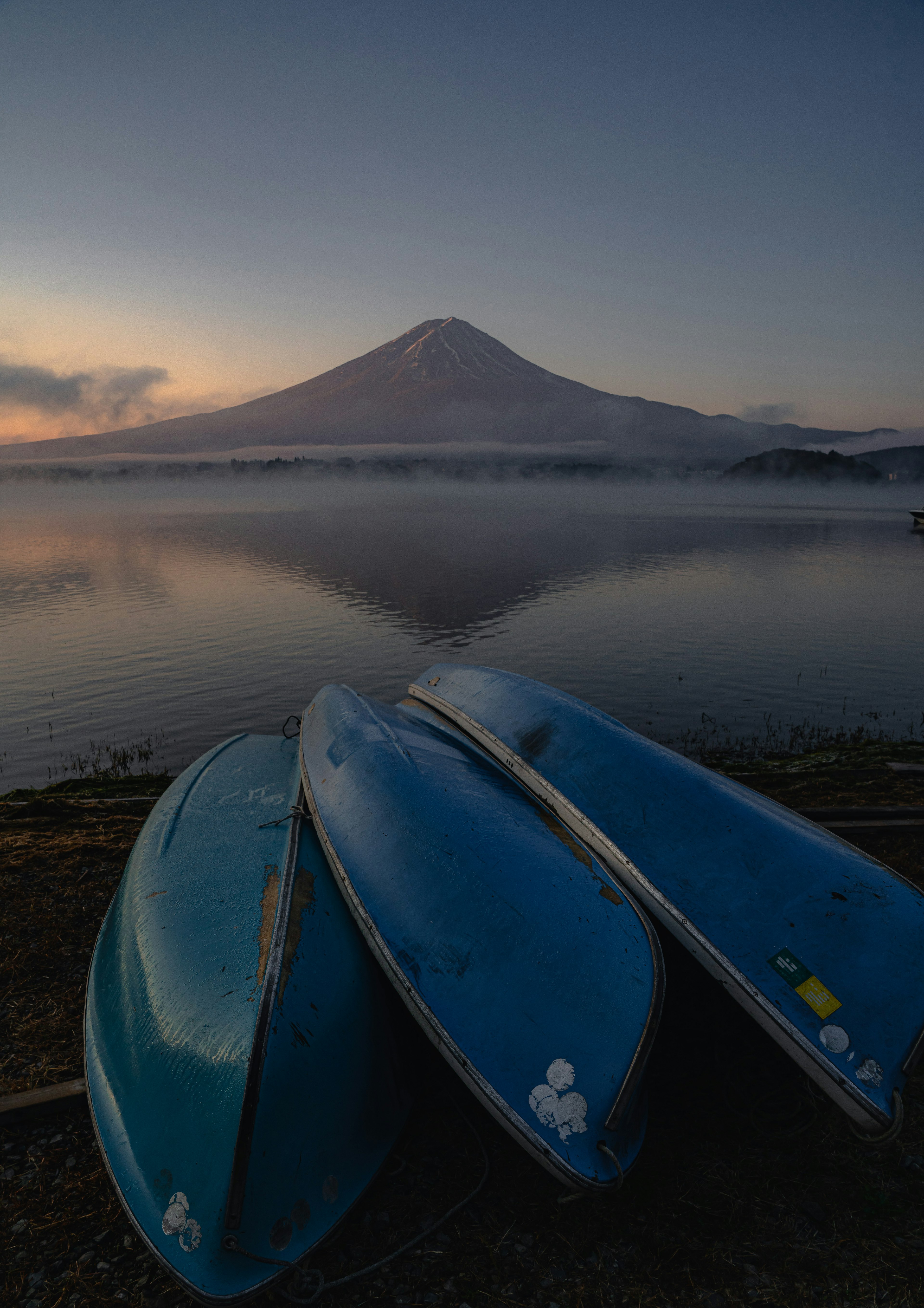 富士山を背景にした青いカヌーが並ぶ静かな湖の風景