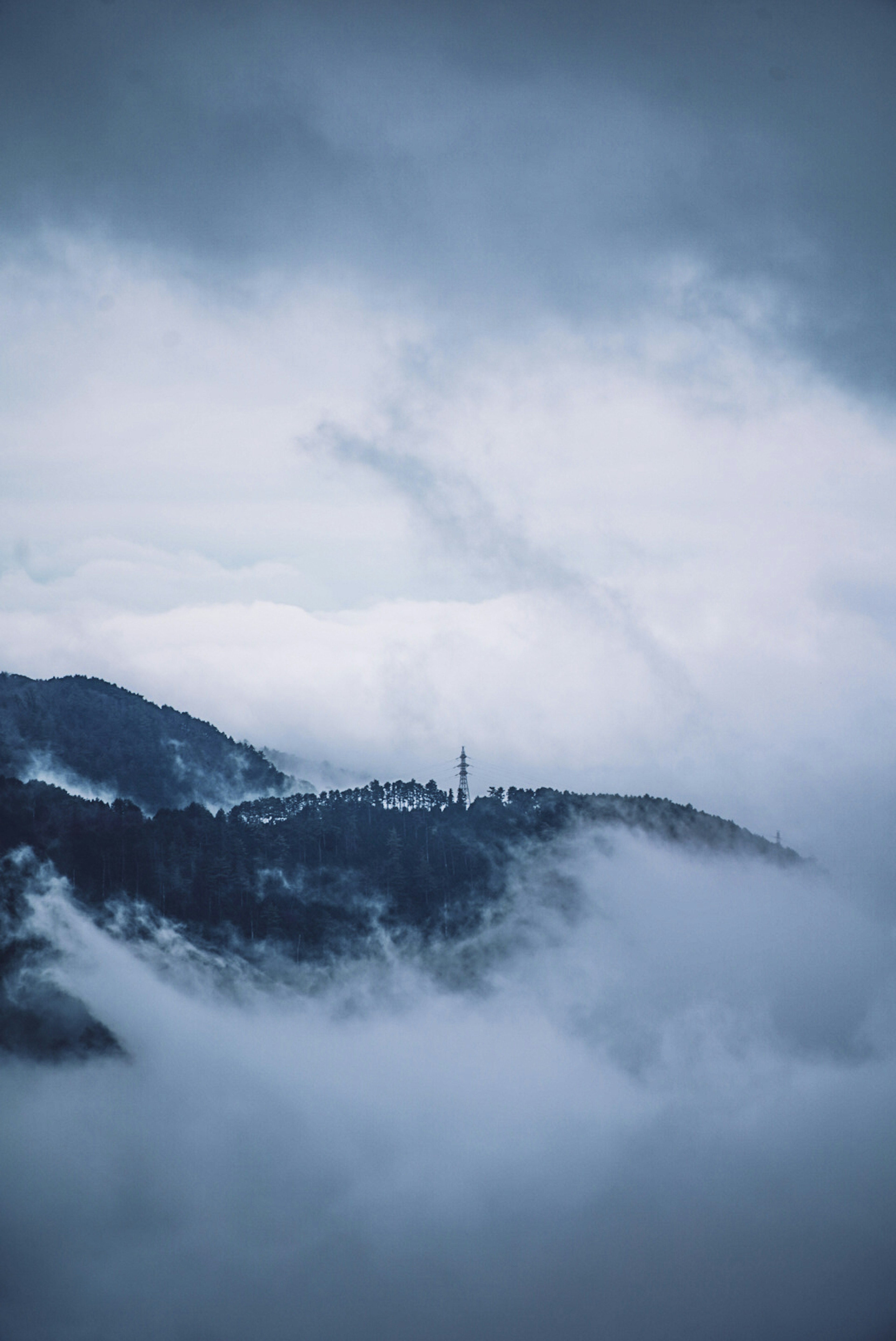 霧に包まれた山々と暗い空の風景