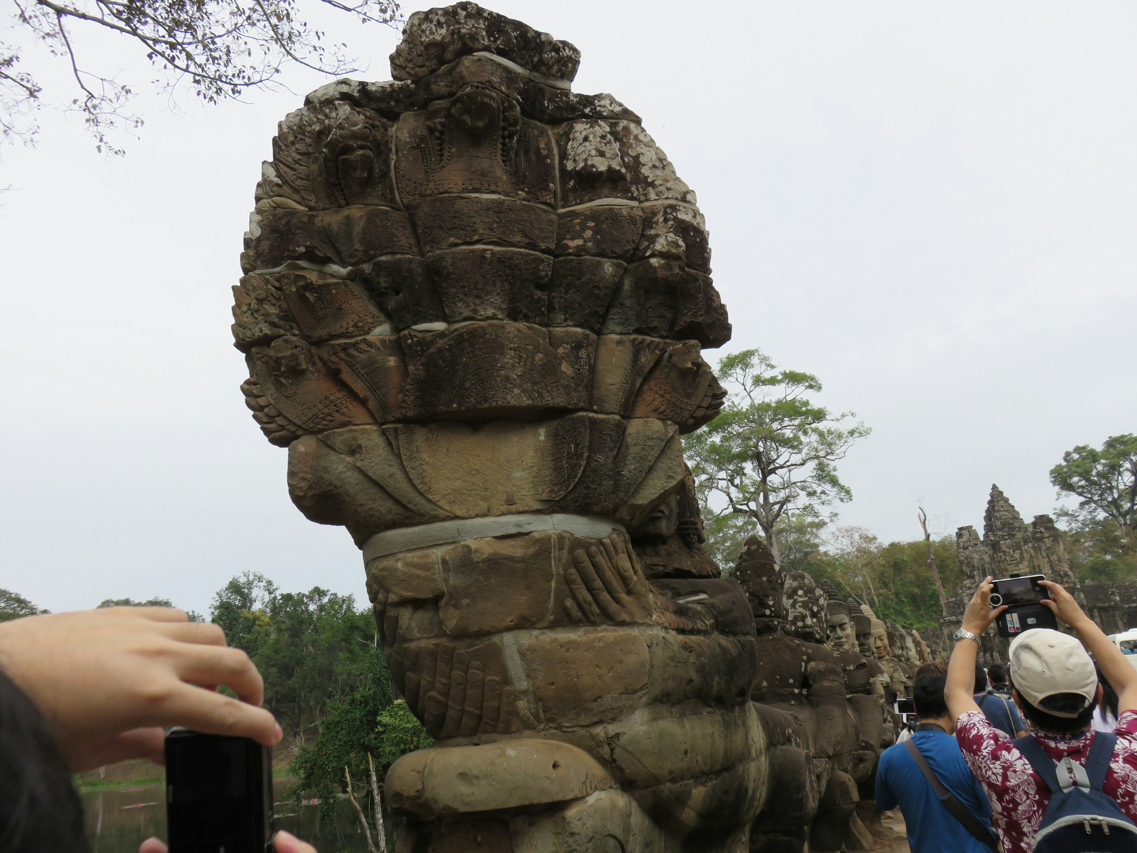 Ancient stone statue with tourists in the background