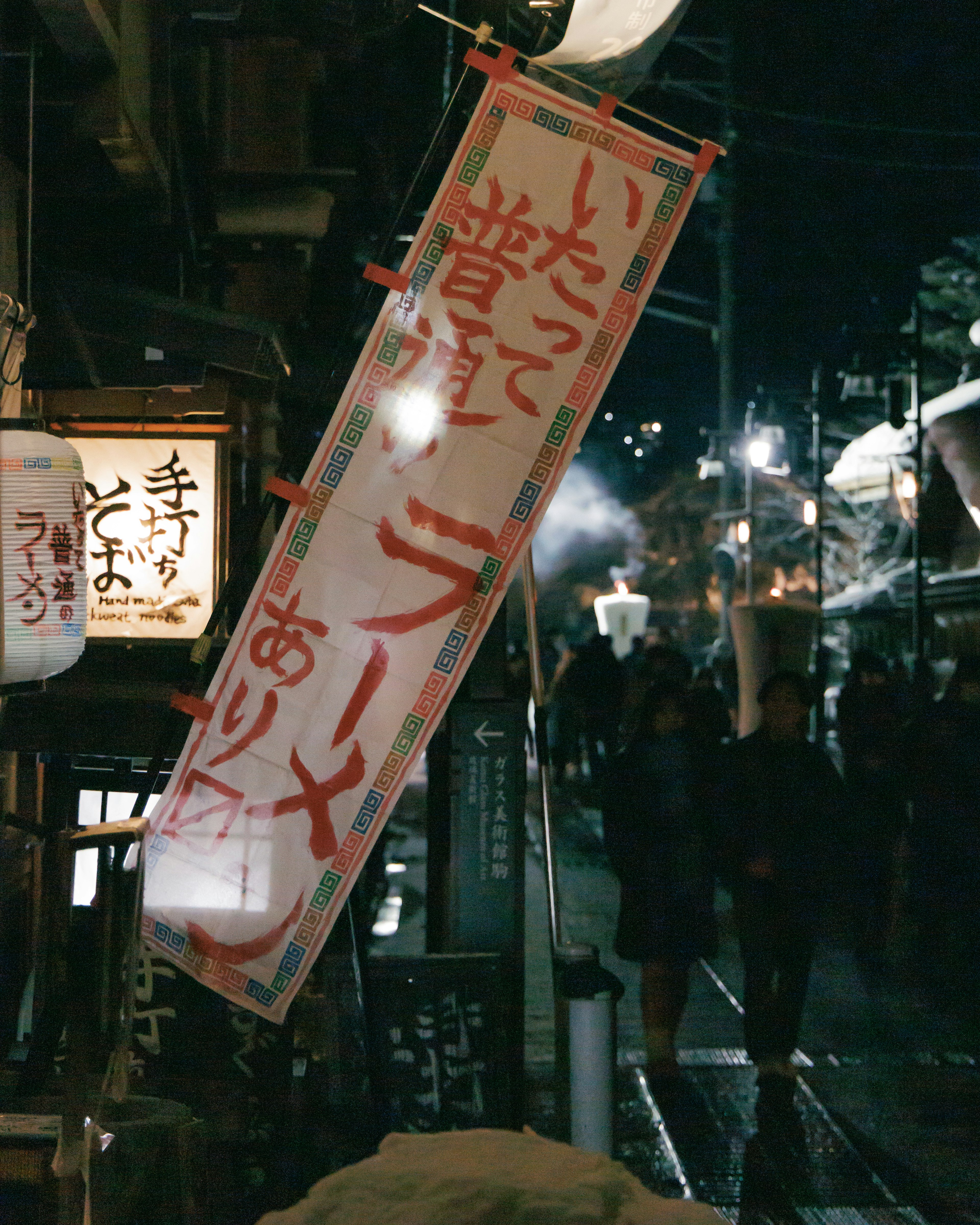 Escena nocturna de una calle con faroles y pancartas