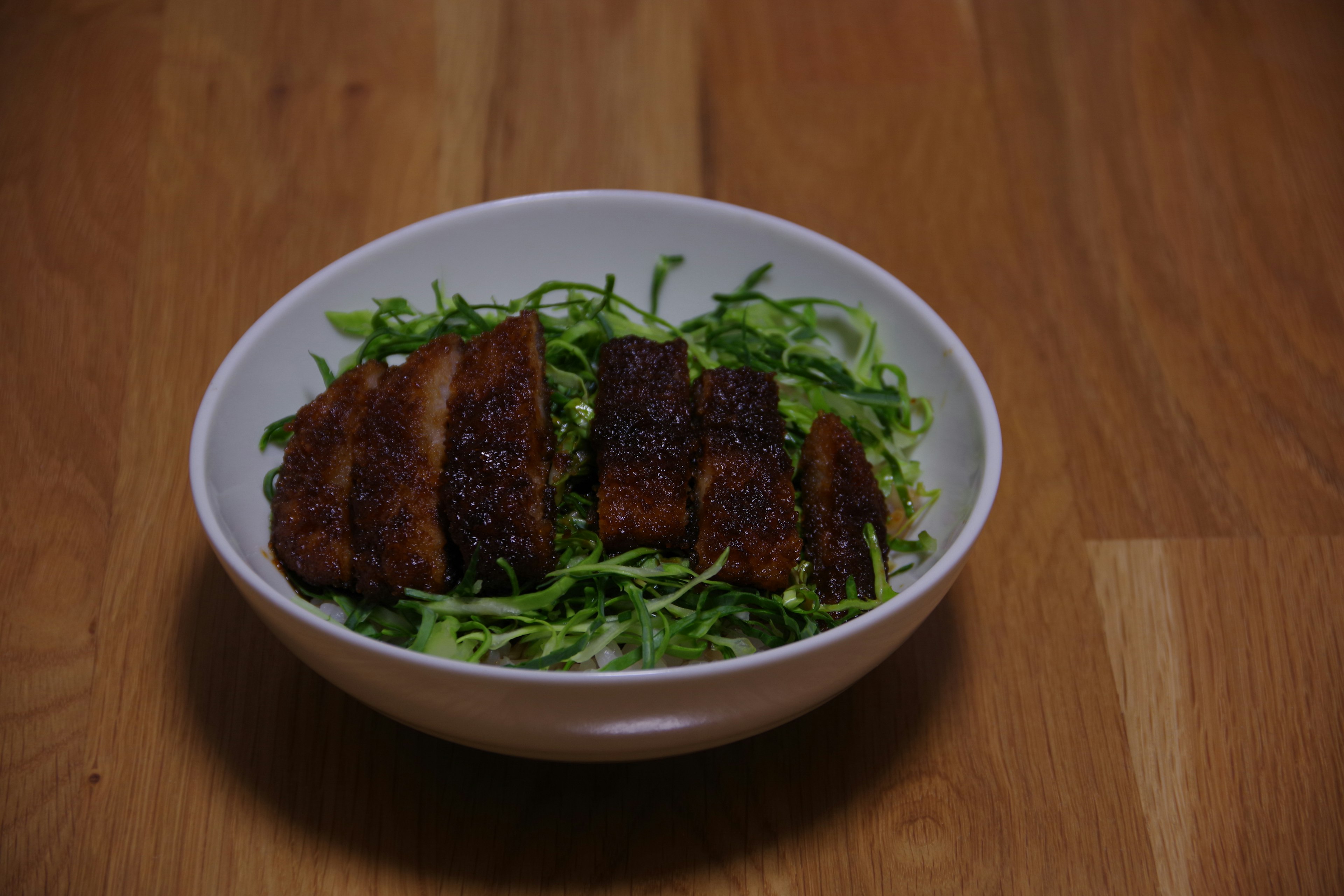 Schüssel mit geraspeltem Salat, belegt mit gegrillten Fleischscheiben