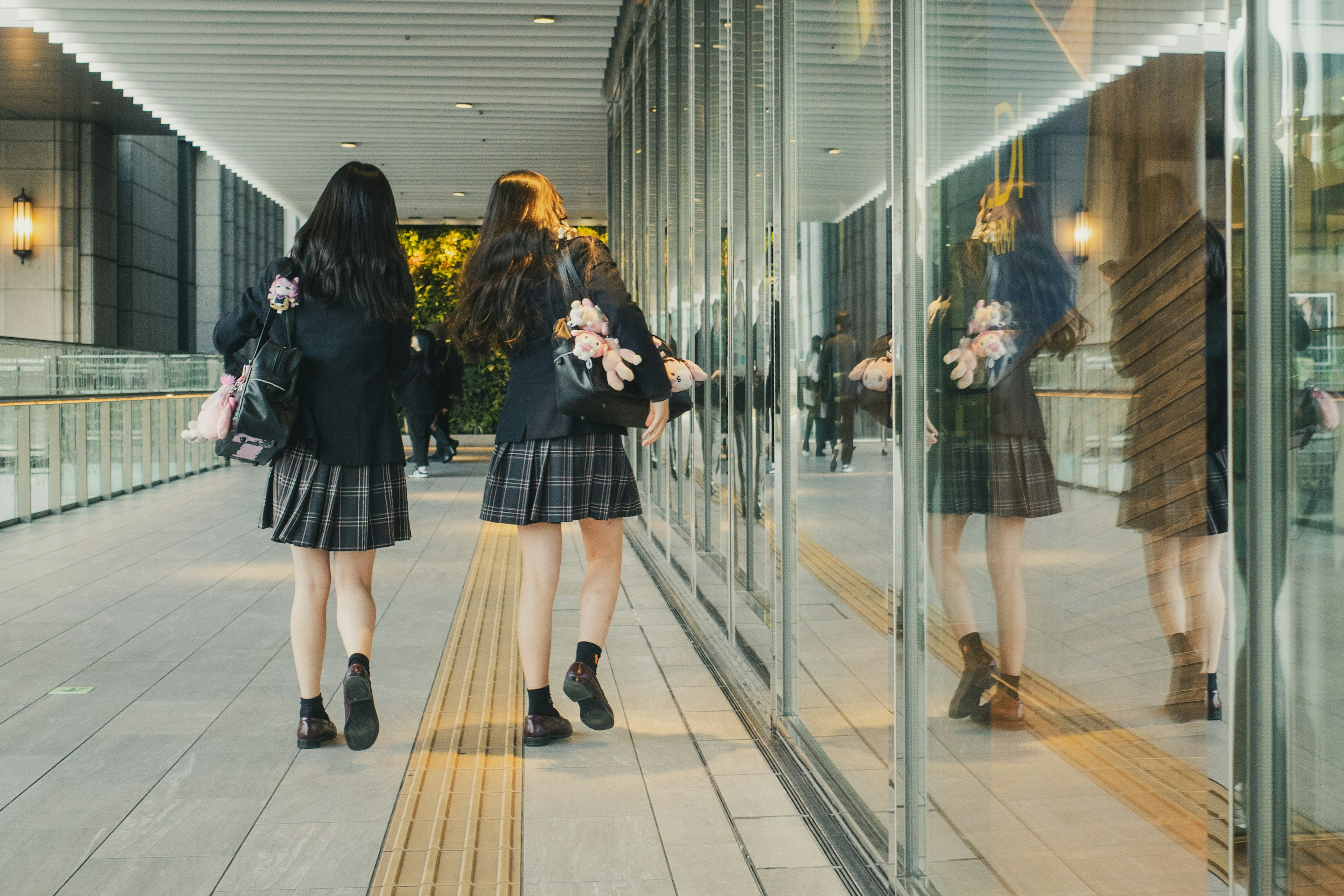 Two students wearing skirts walking together in a modern urban setting