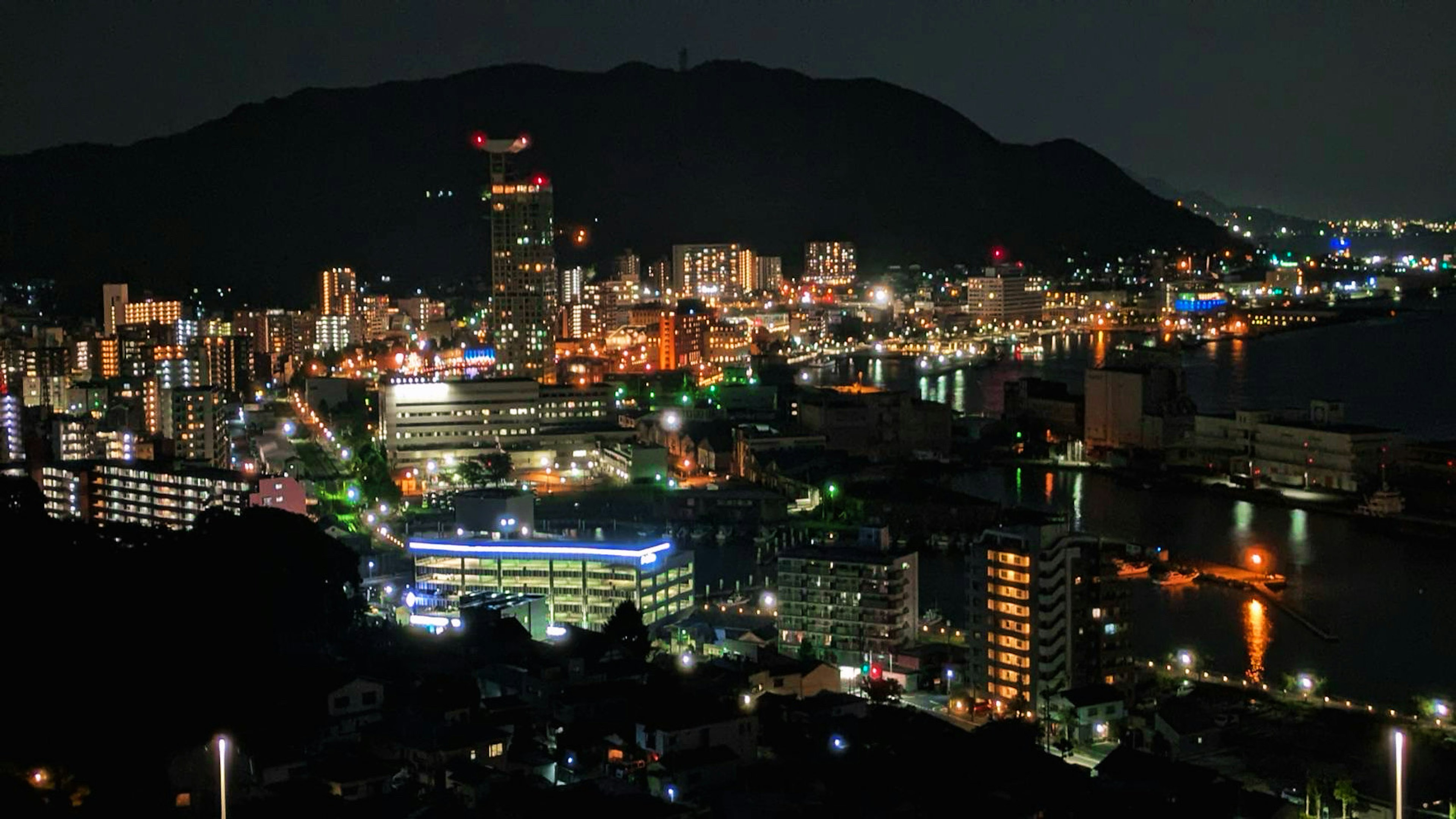 Hermosa vista nocturna de una ciudad con rascacielos y montañas de fondo