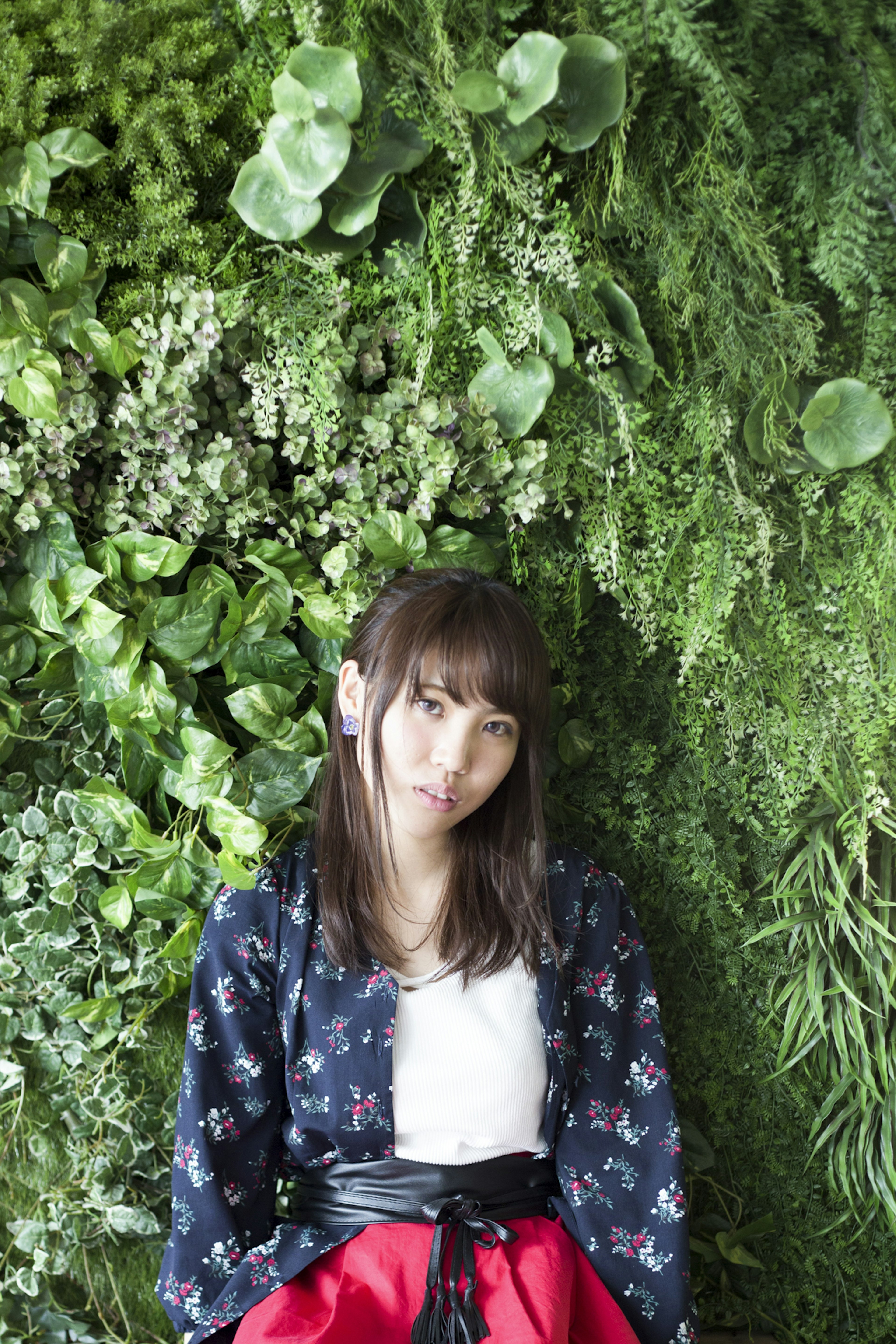 Woman standing in front of a green wall wearing floral-patterned clothing