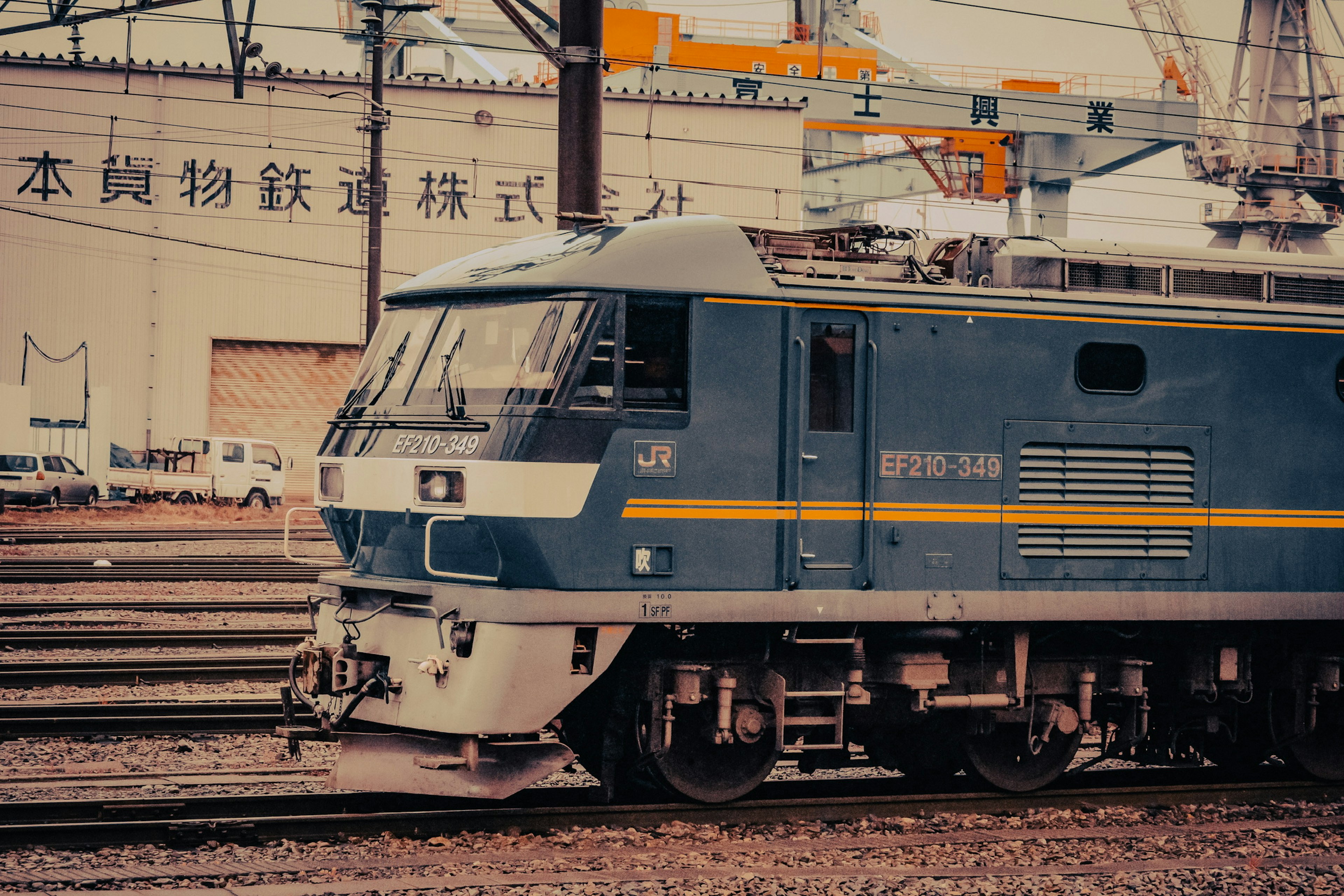 青い電車が線路の横に停車している工場の背景