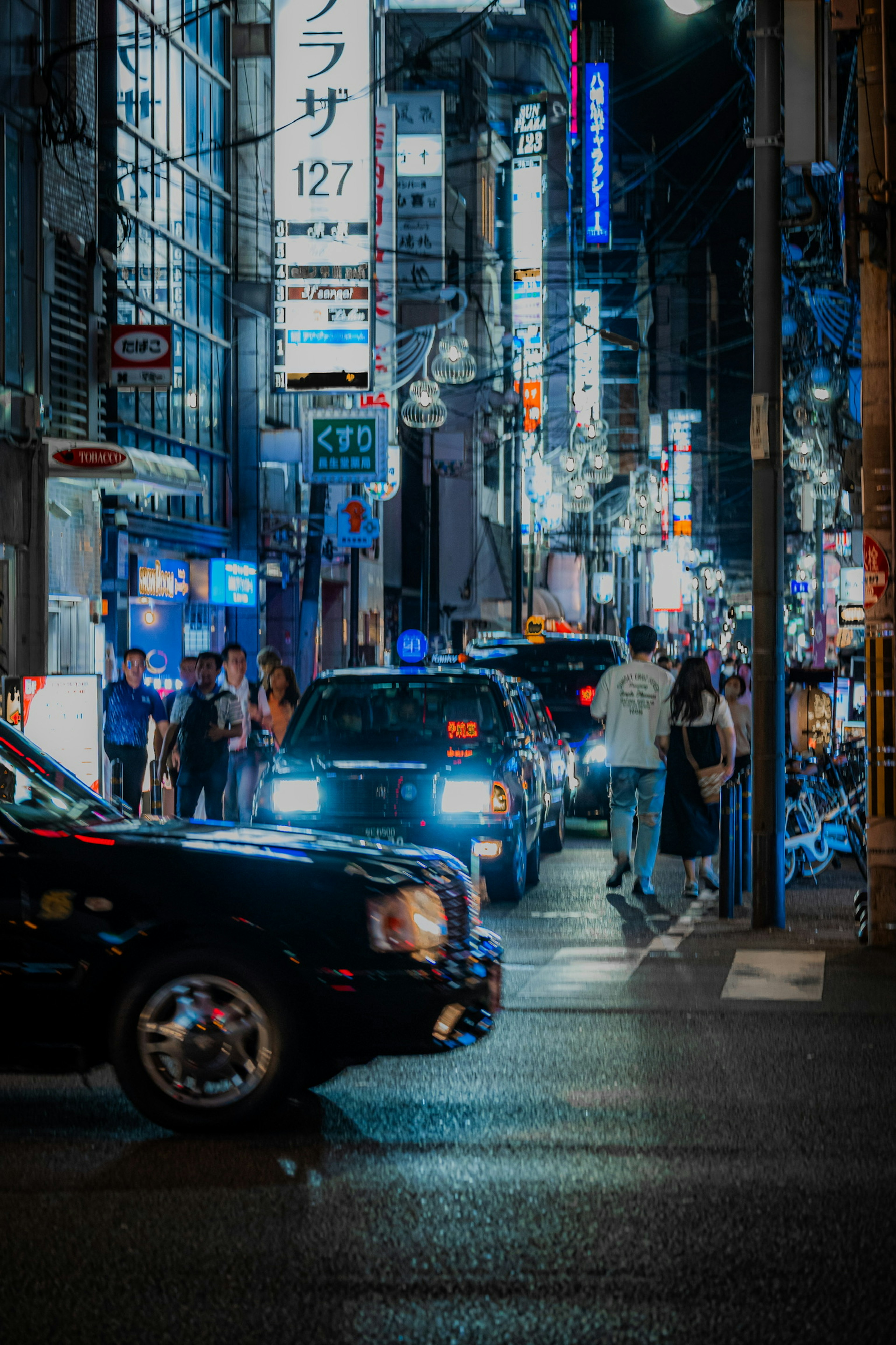 Nighttime urban scene with taxis and pedestrians