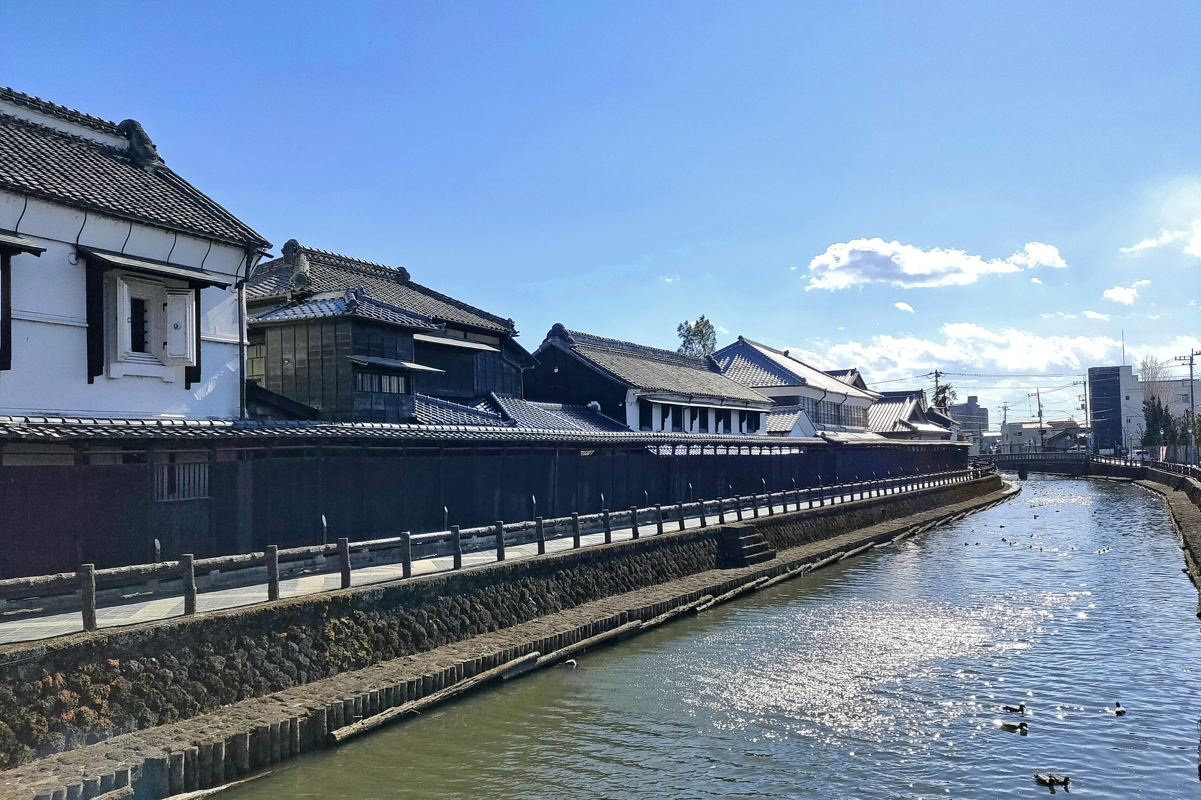 Traditional Japanese buildings along a river under a blue sky