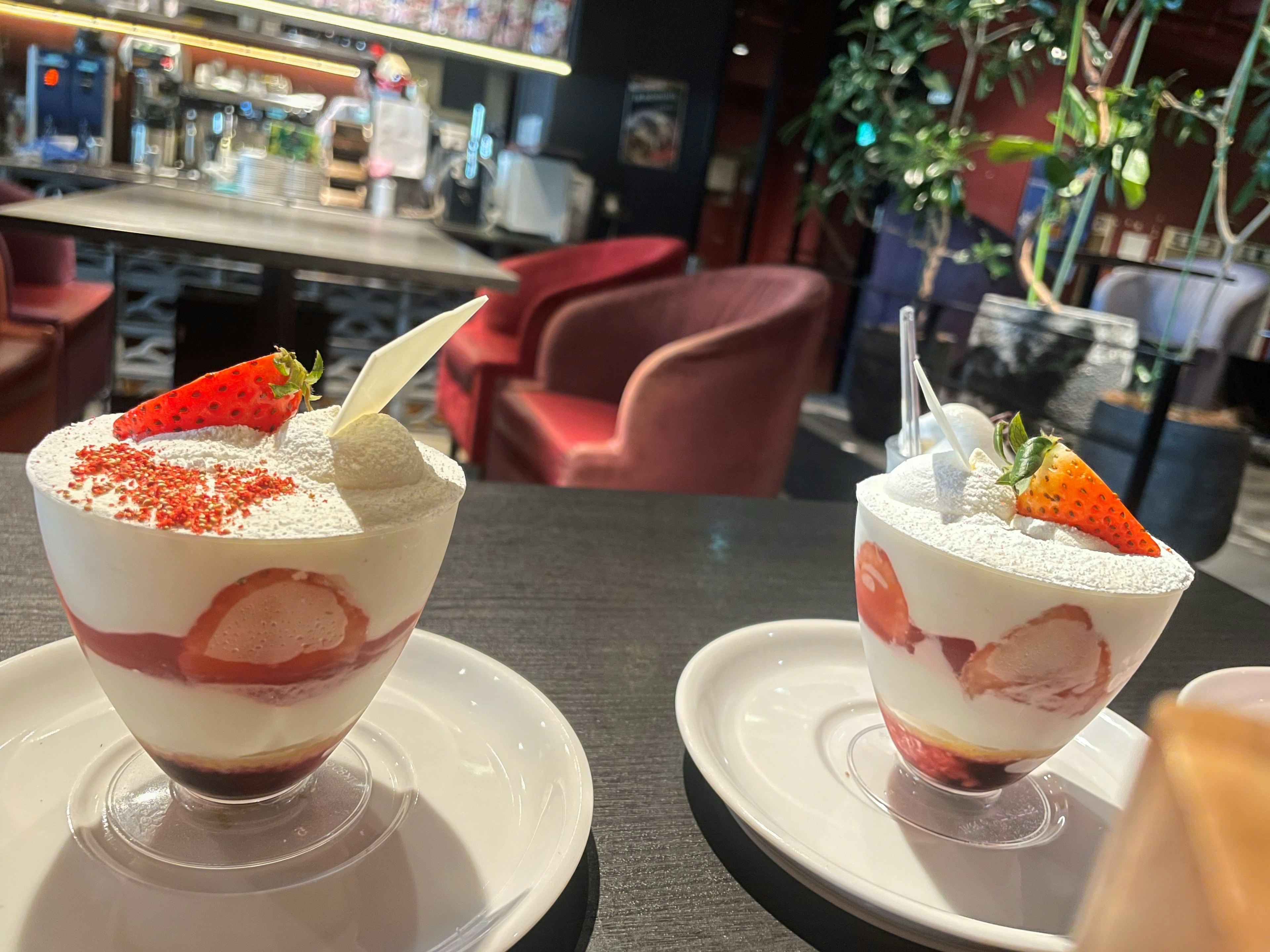 Dos postres de fresa cubiertos con crema blanca sobre una mesa