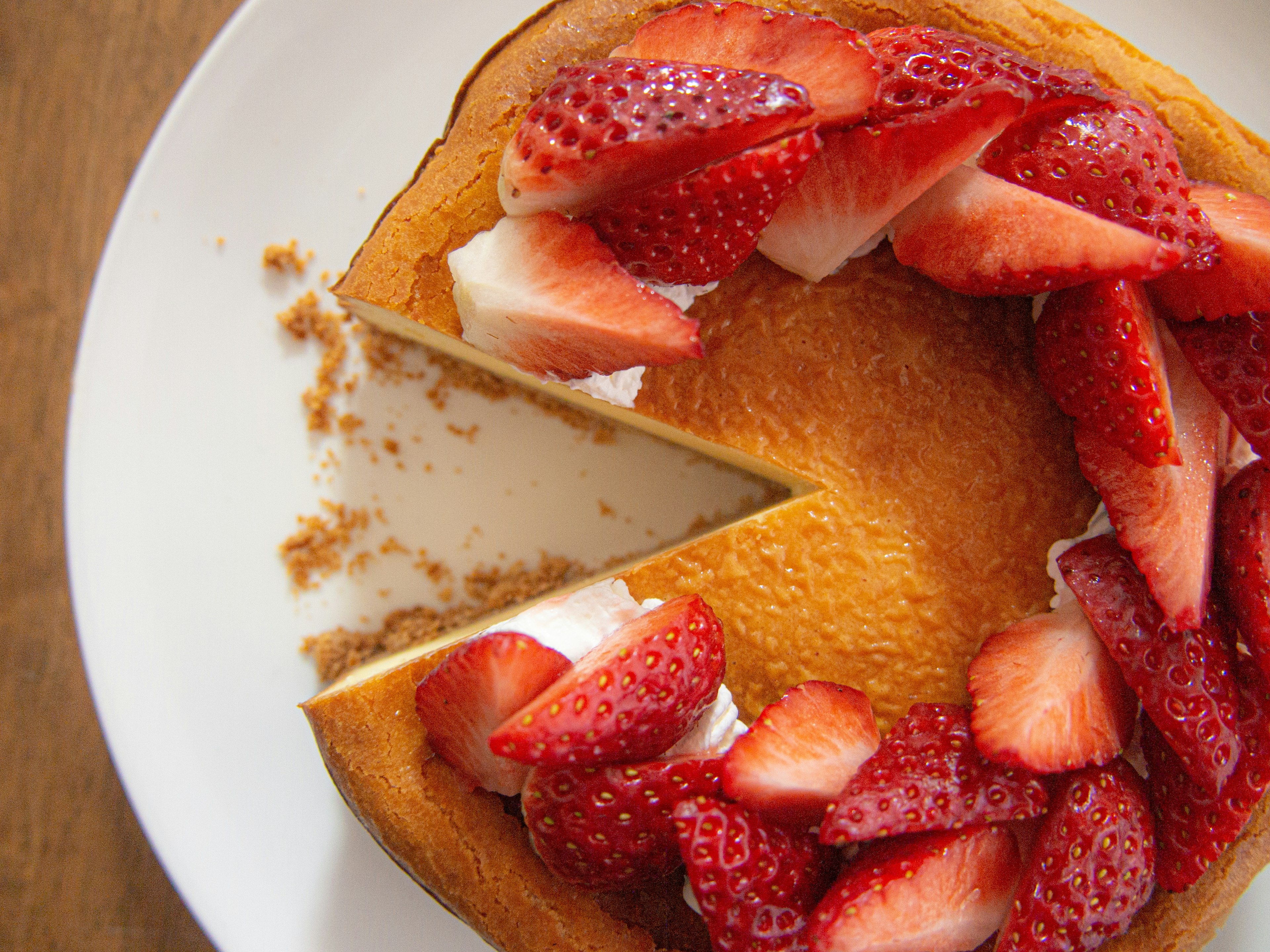 A cake topped with strawberries showing a slice cut out