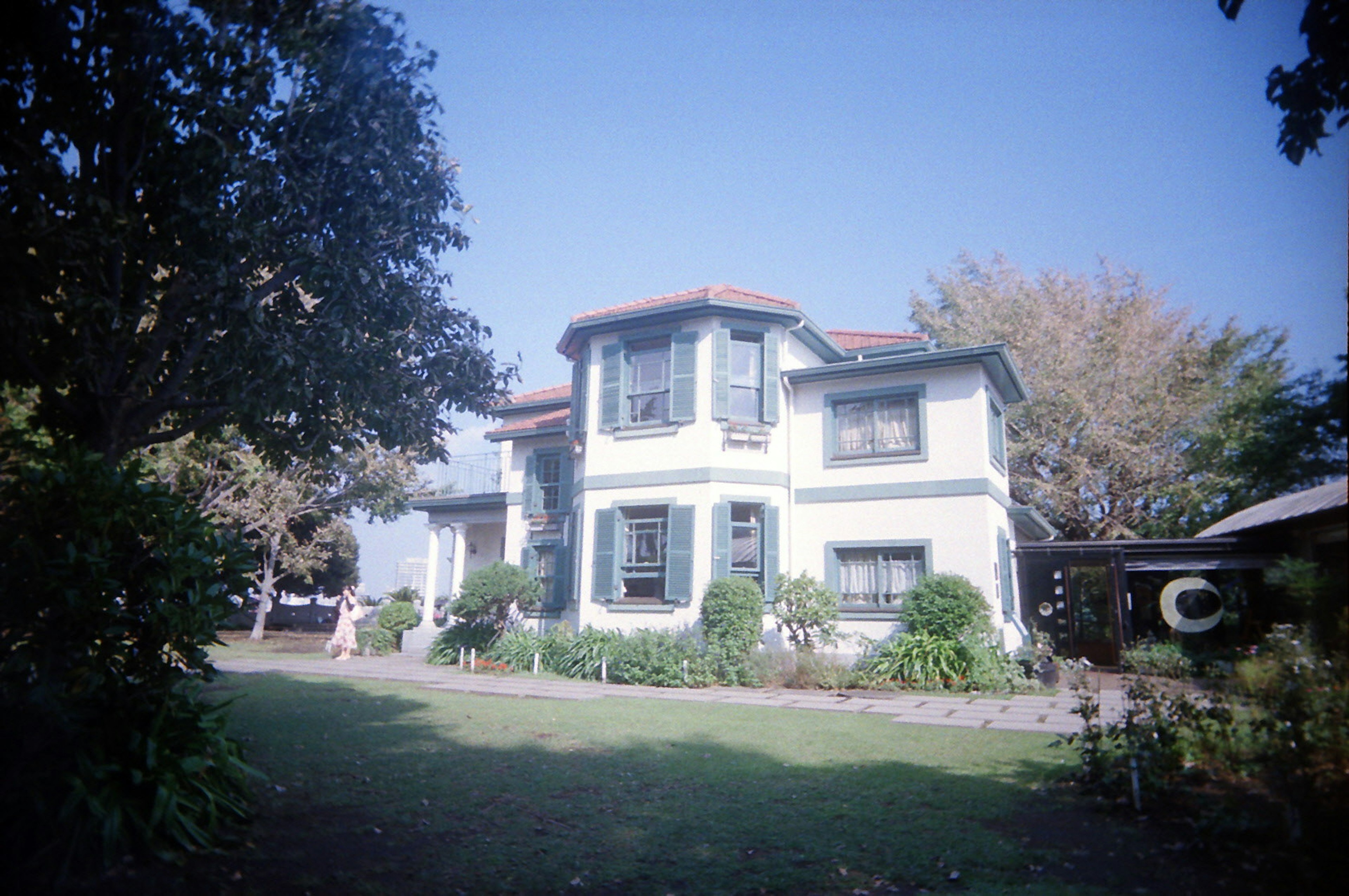 Ein weißes Haus mit grünem Garten unter einem blauen Himmel