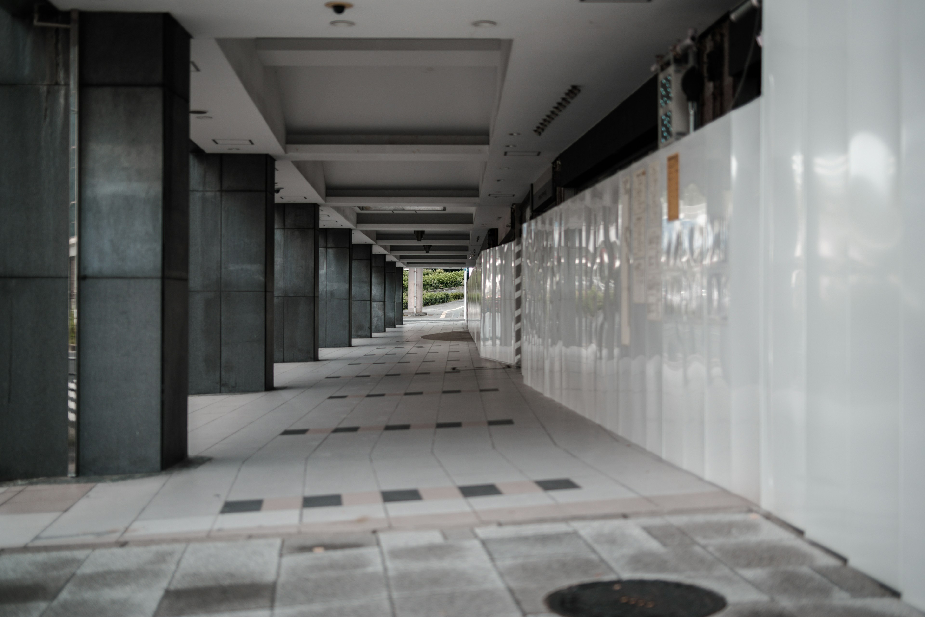 A corridor featuring white walls and black pillars