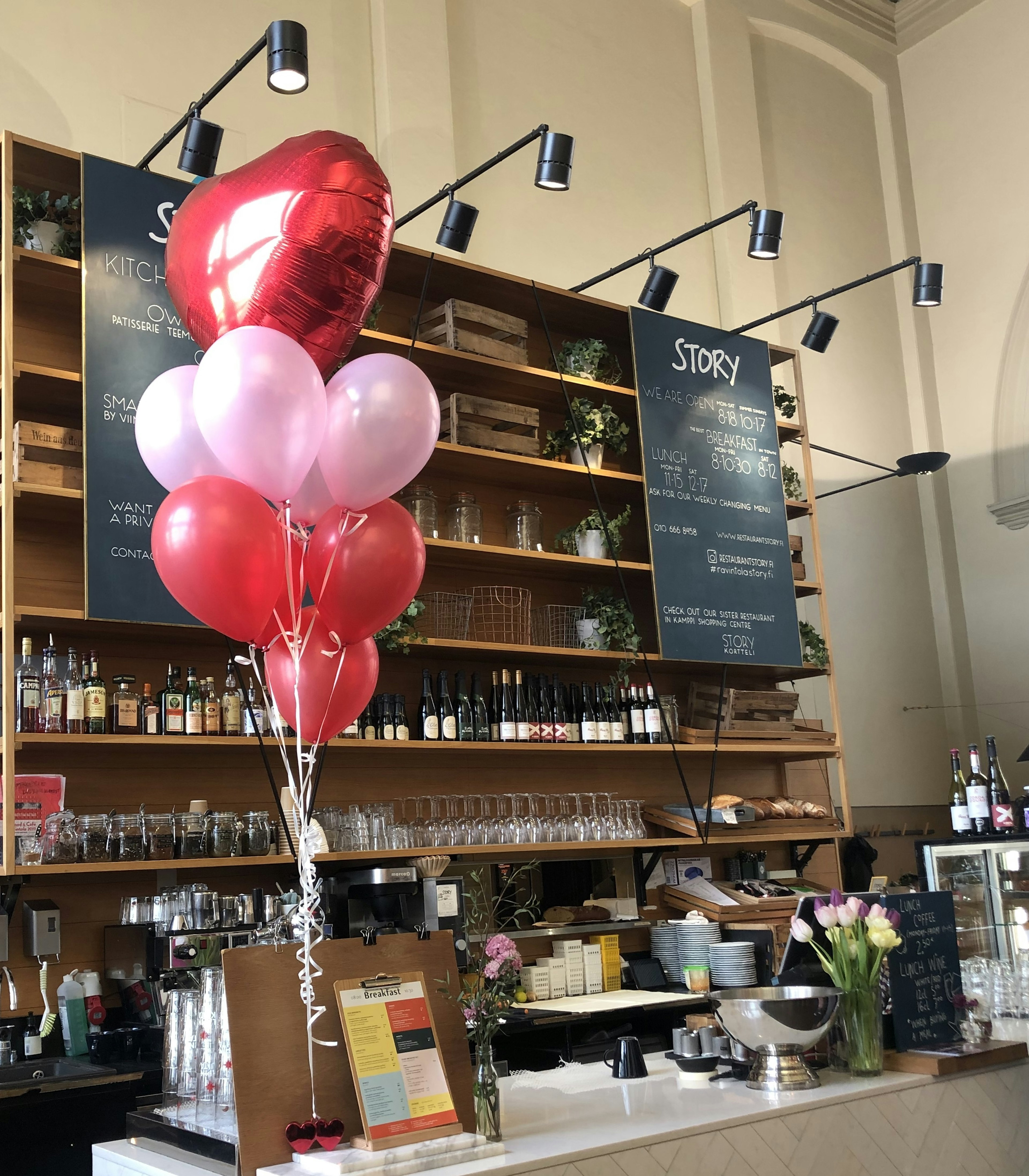 Interno di un caffè con palloncini a forma di cuore rossi e palloncini rosa