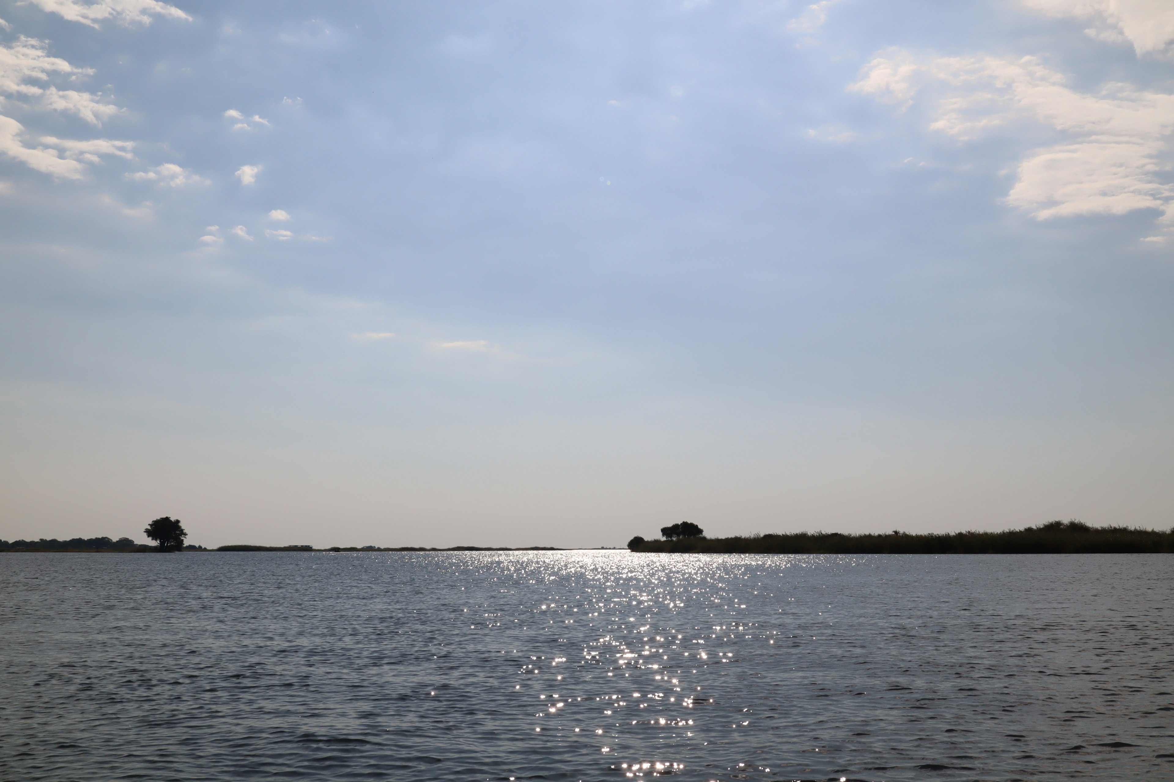 Calm water reflecting sunlight with a wide blue sky