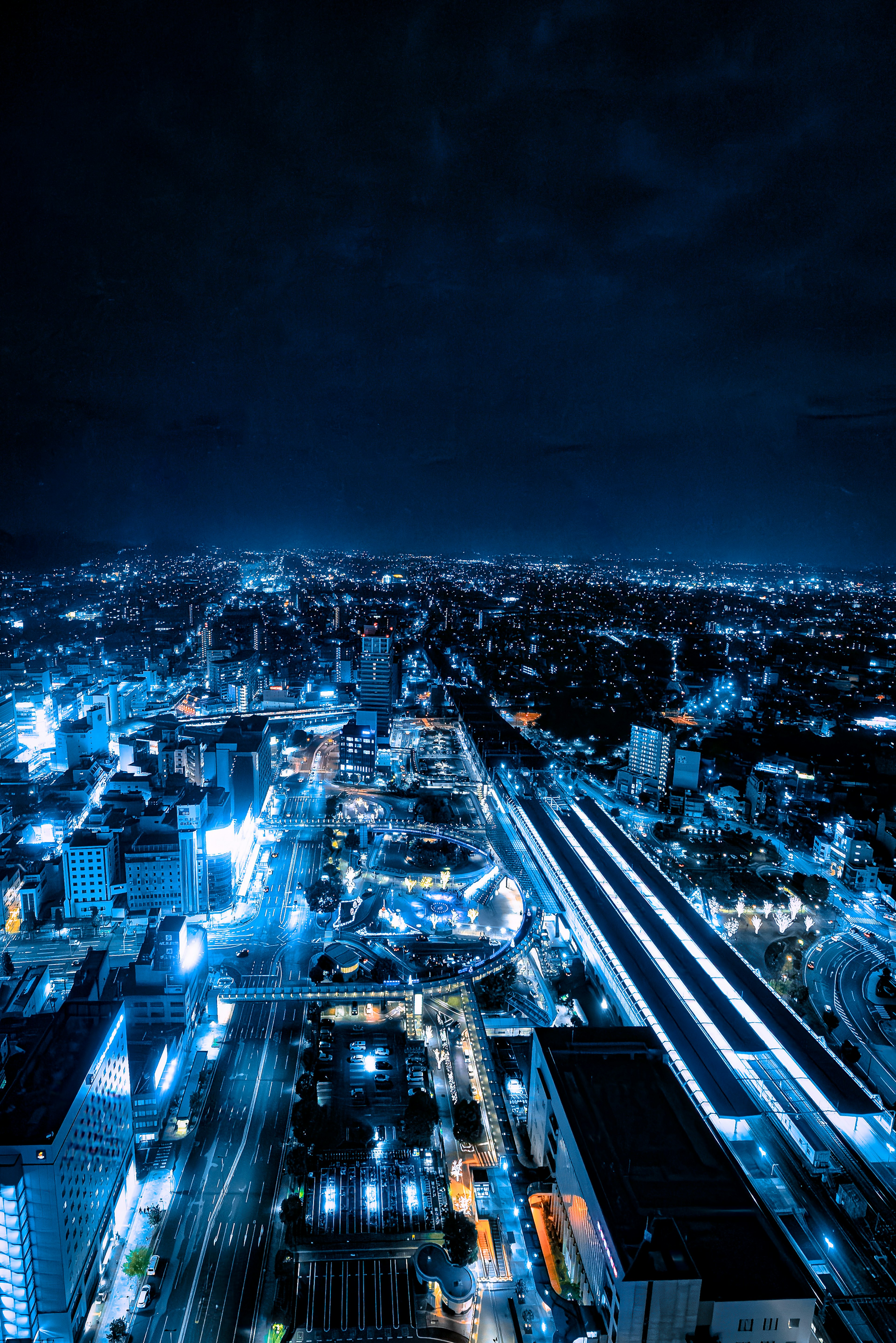 Paesaggio urbano notturno con luci blu e silhouette di edifici contro il cielo scuro