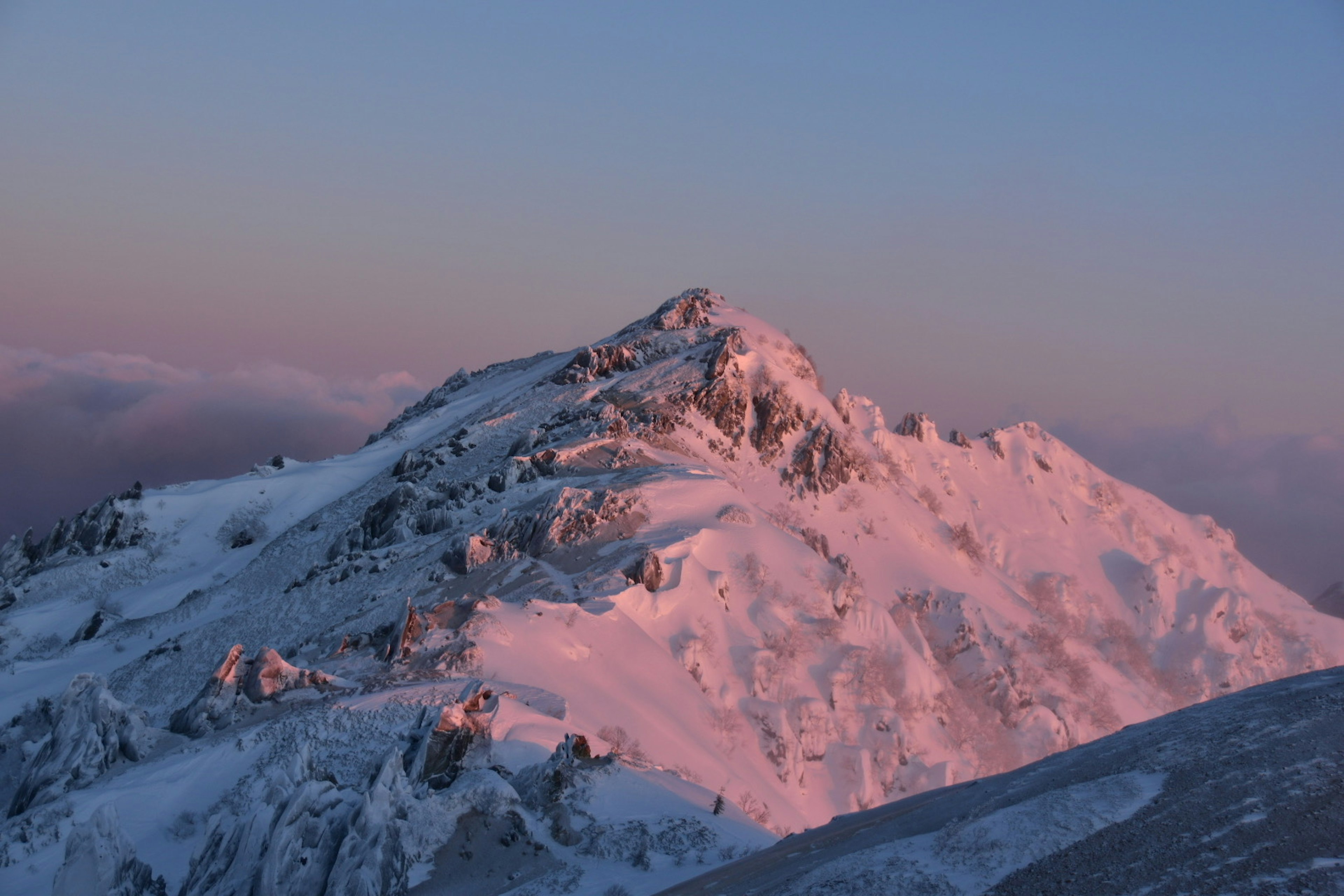 Cima de montaña cubierta de nieve iluminada por el atardecer