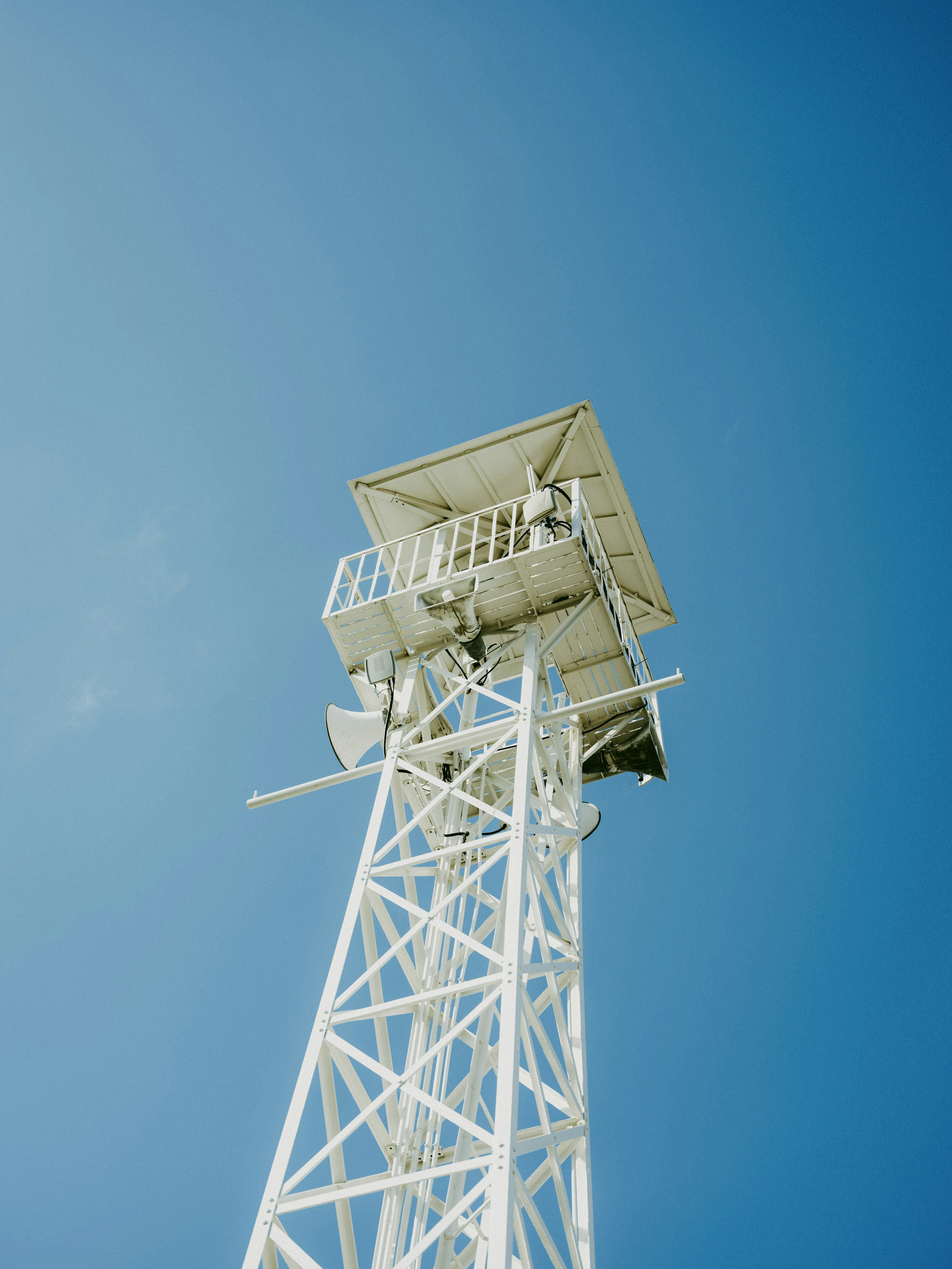 Una torre de comunicación blanca que se eleva en un cielo azul claro