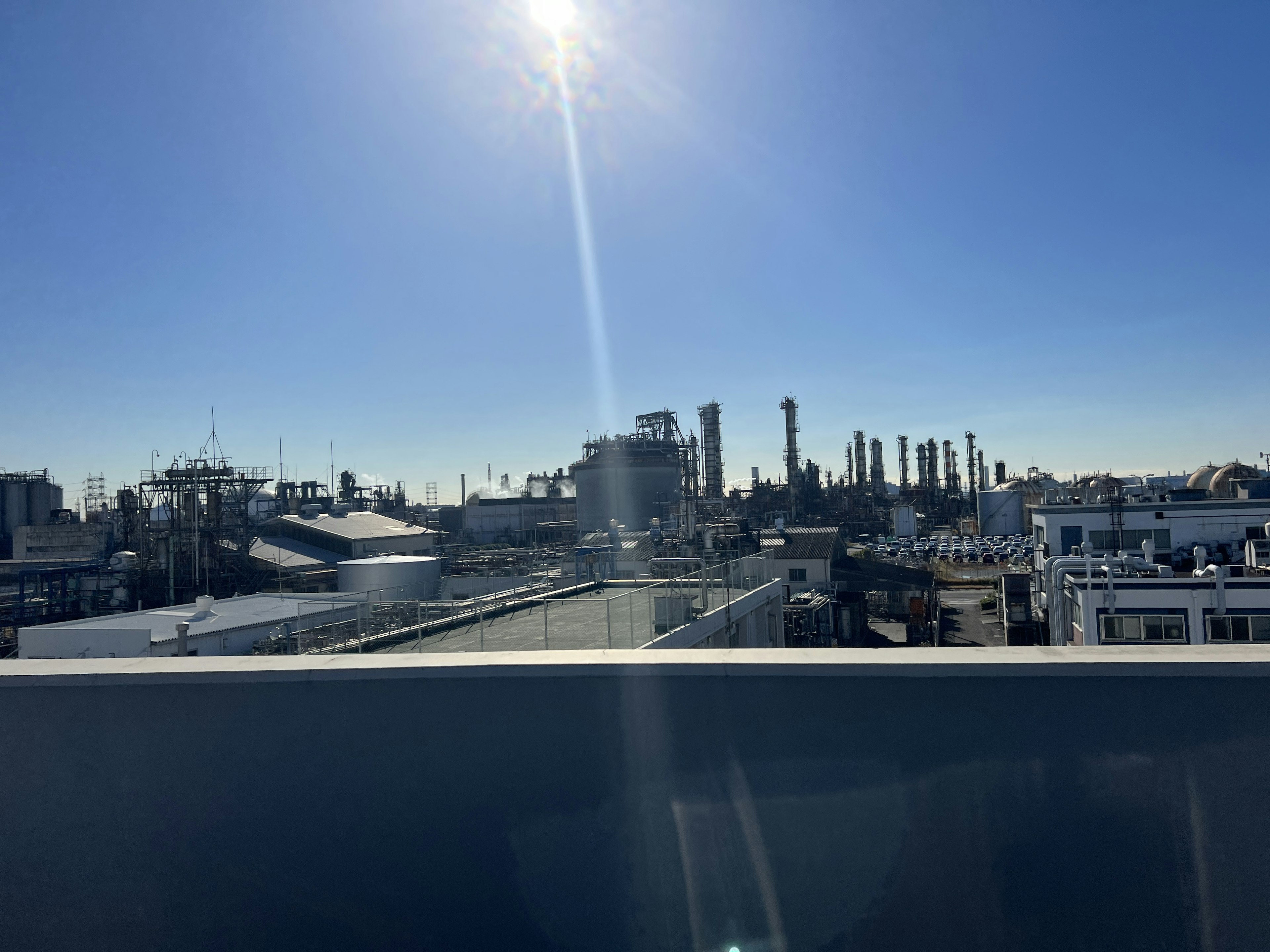 Industrial landscape under a clear blue sky featuring smokestacks and buildings