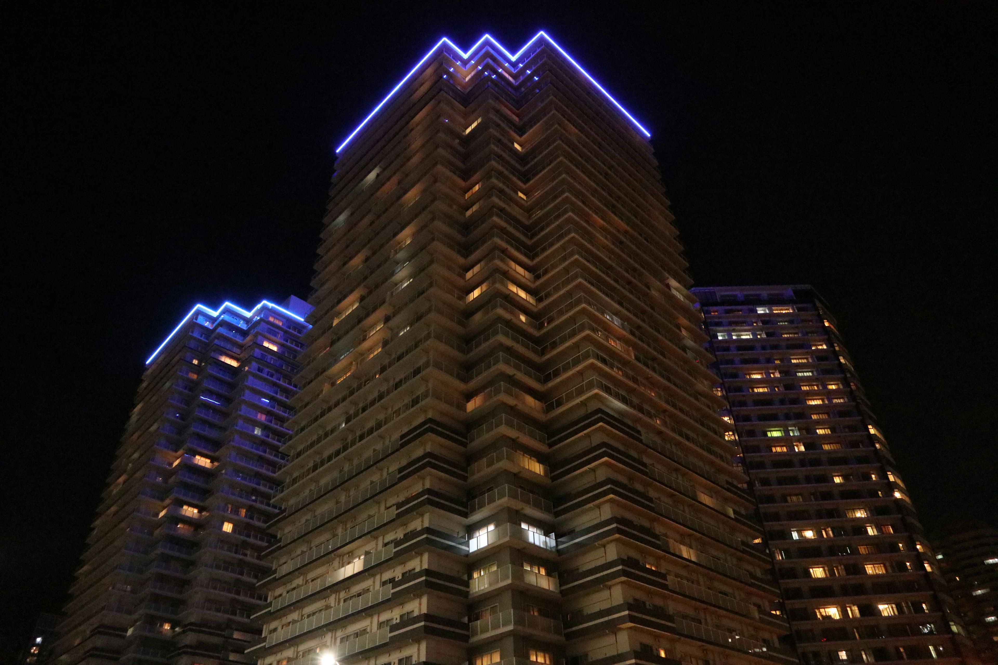 Gedung pencakar langit yang diterangi cahaya biru di malam hari