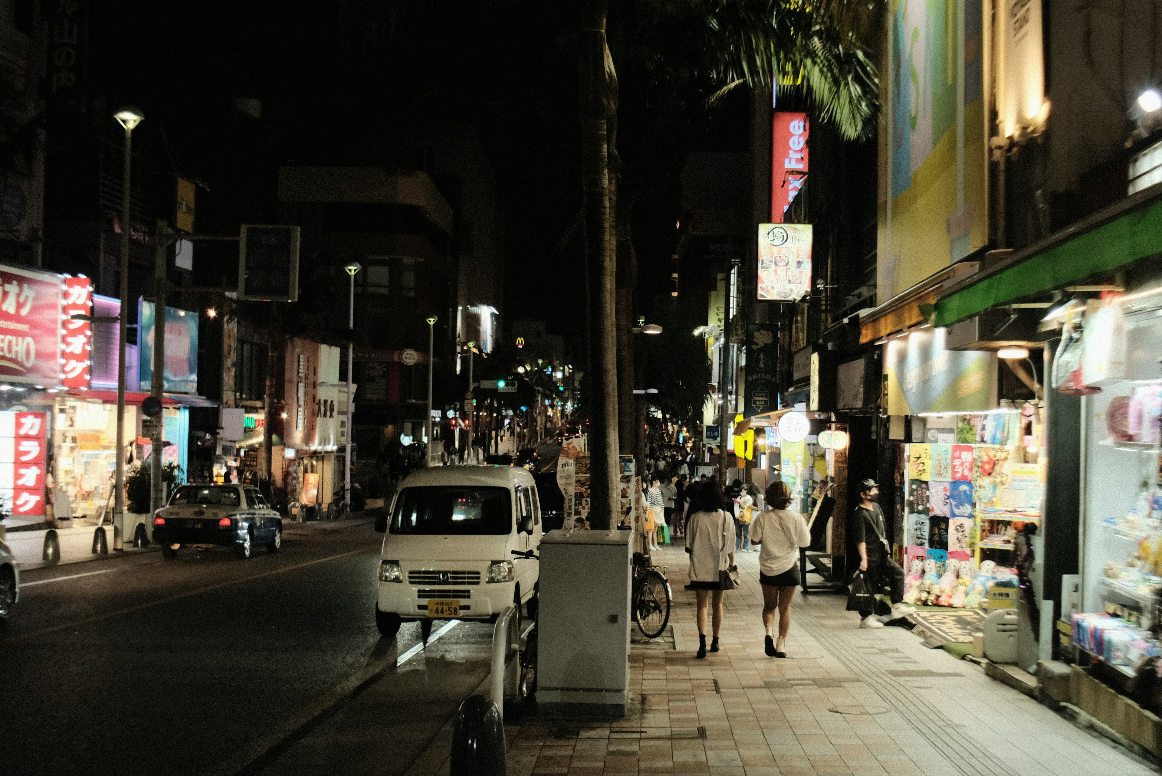 Orang-orang berjalan di jalan yang ramai di malam hari dengan tanda-tanda terang