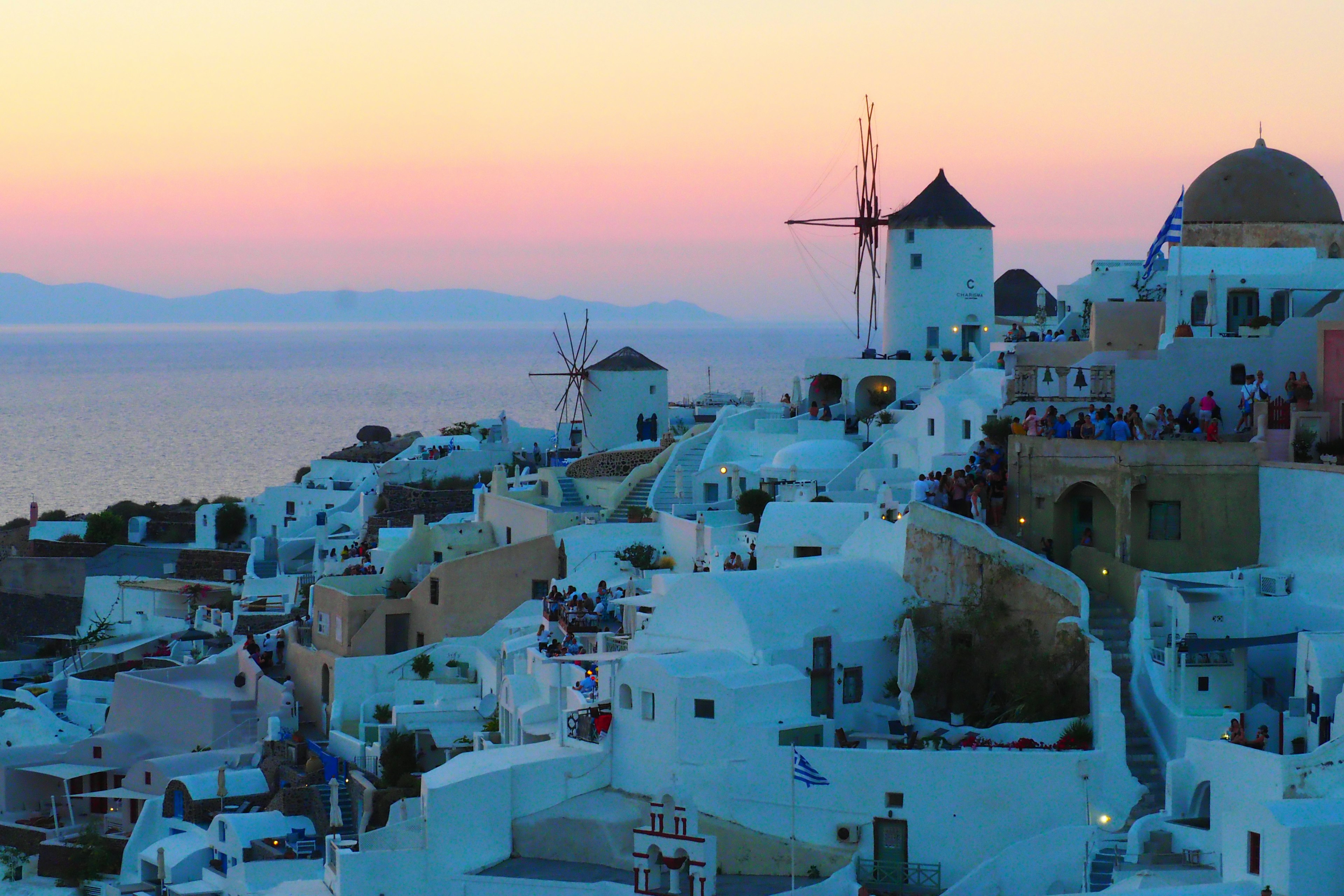 Pemandangan matahari terbenam yang indah di Santorini dengan bangunan putih dan kincir angin