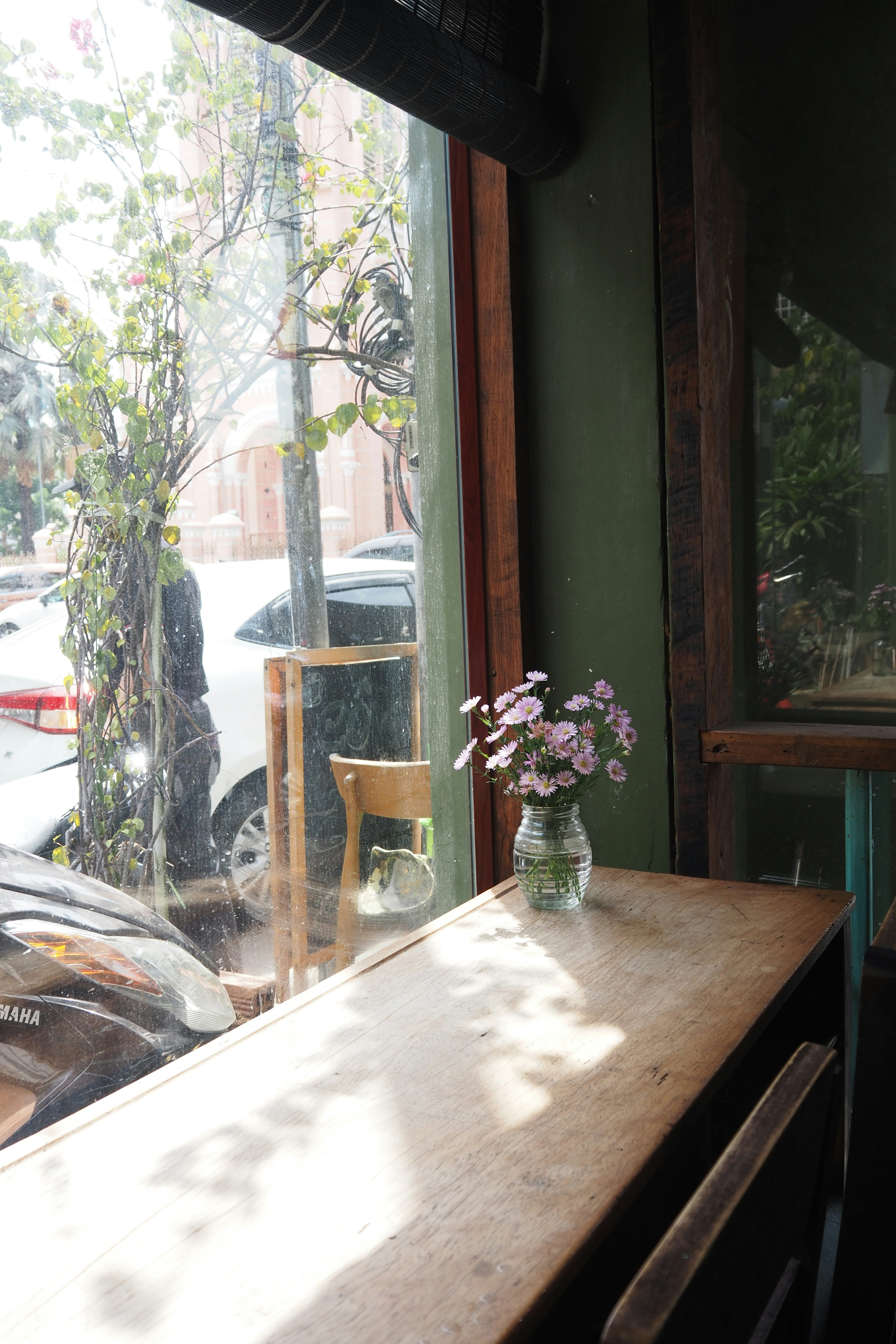 Un pequeño jarrón con flores en una mesa de café junto a la ventana