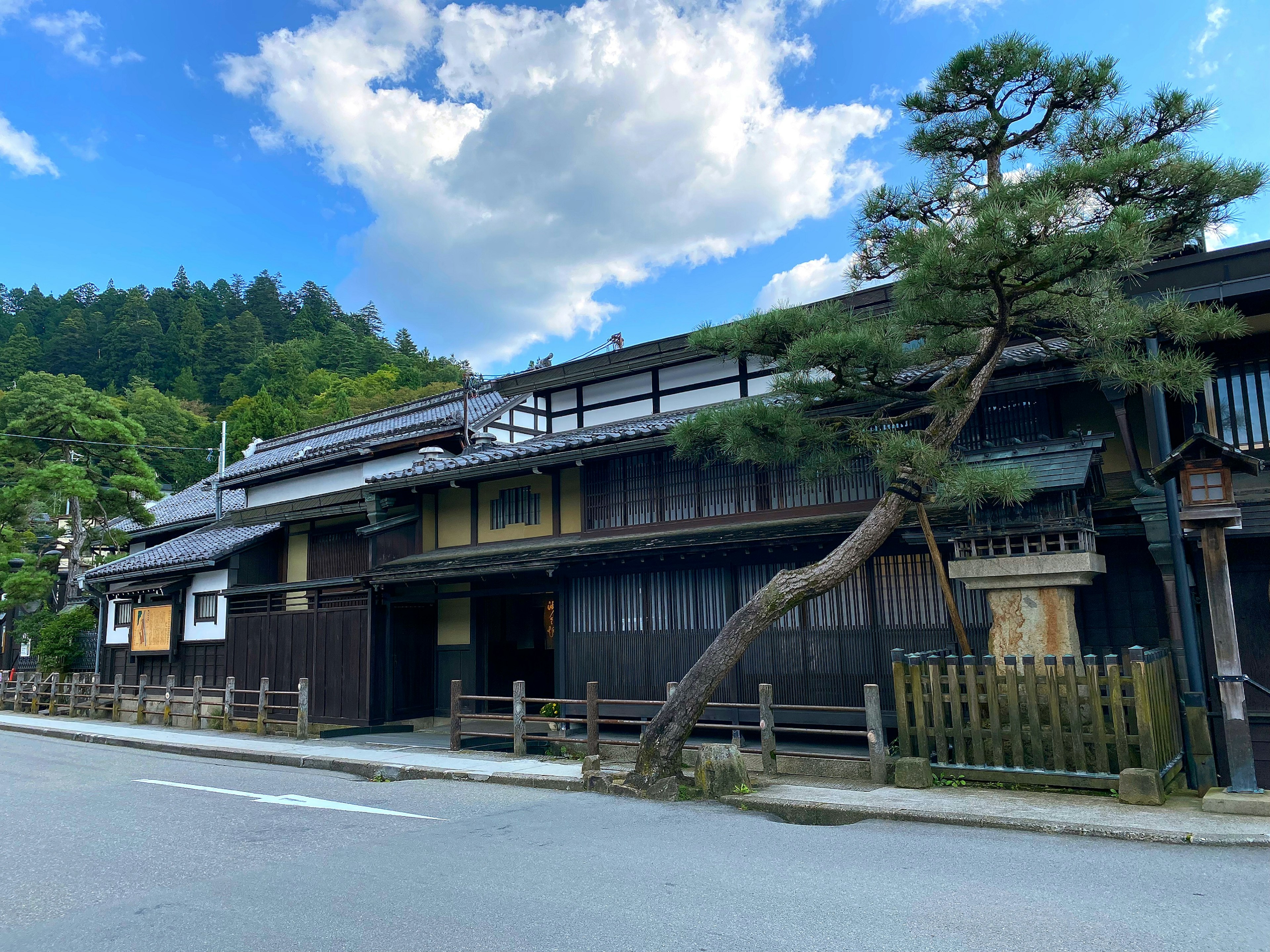 Traditional Japanese house with a leaning pine tree blue sky and white clouds