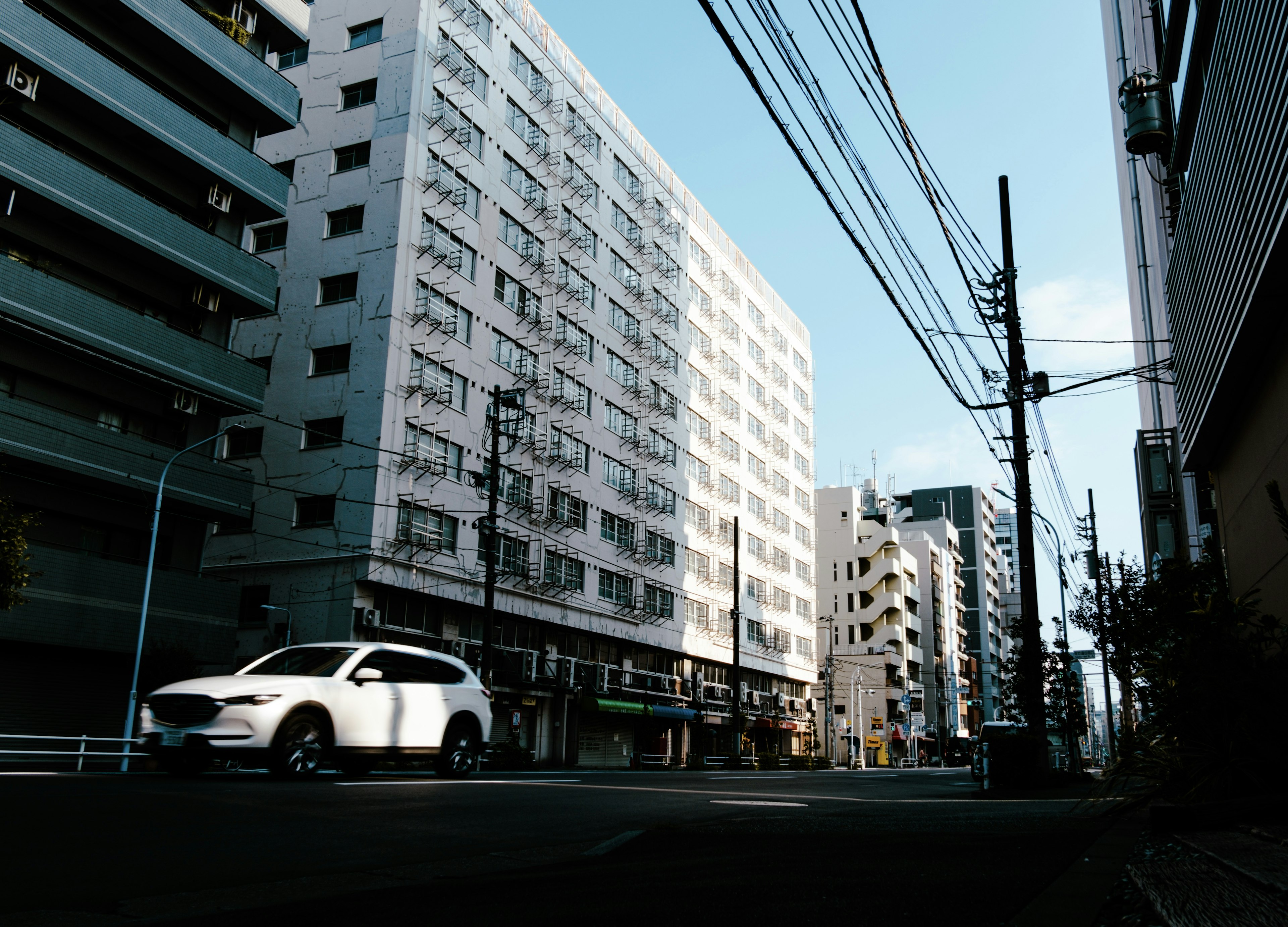 Vue de rue avec une voiture blanche et des immeubles élevés