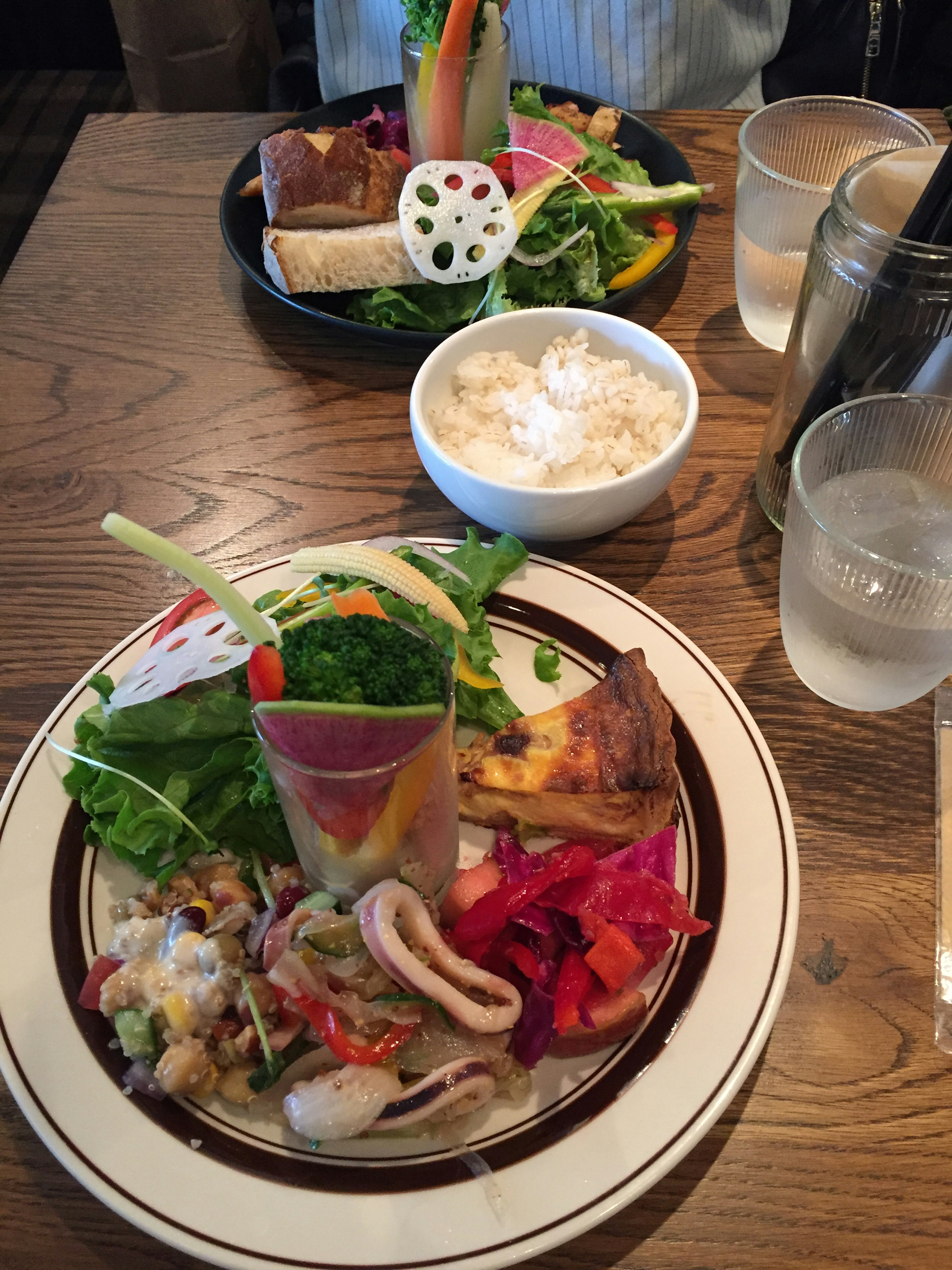 色とりどりの野菜とシーフードが盛り付けられた料理のプレートと白いご飯があるテーブル