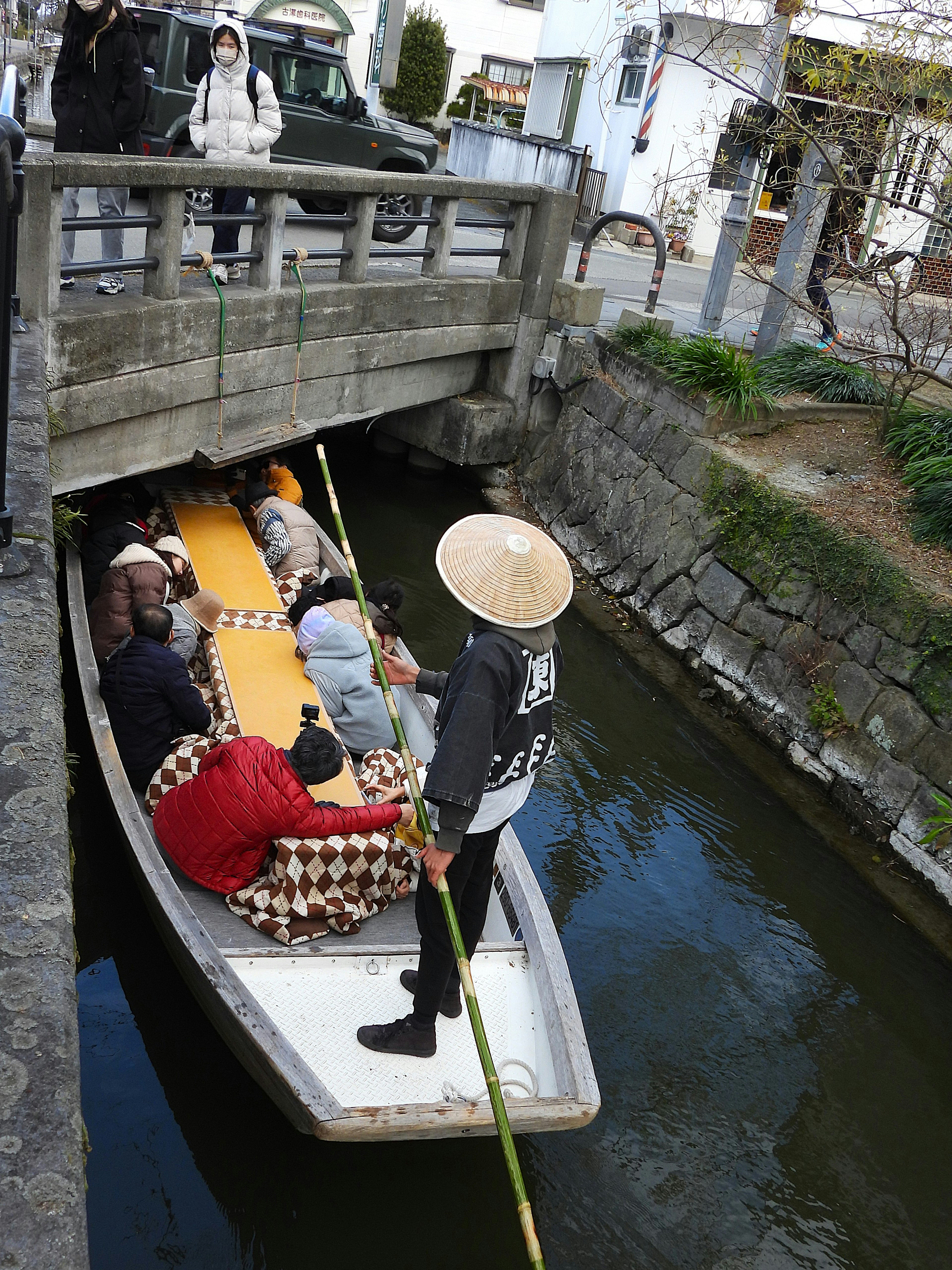 Tourists on a small boat passing under a bridge