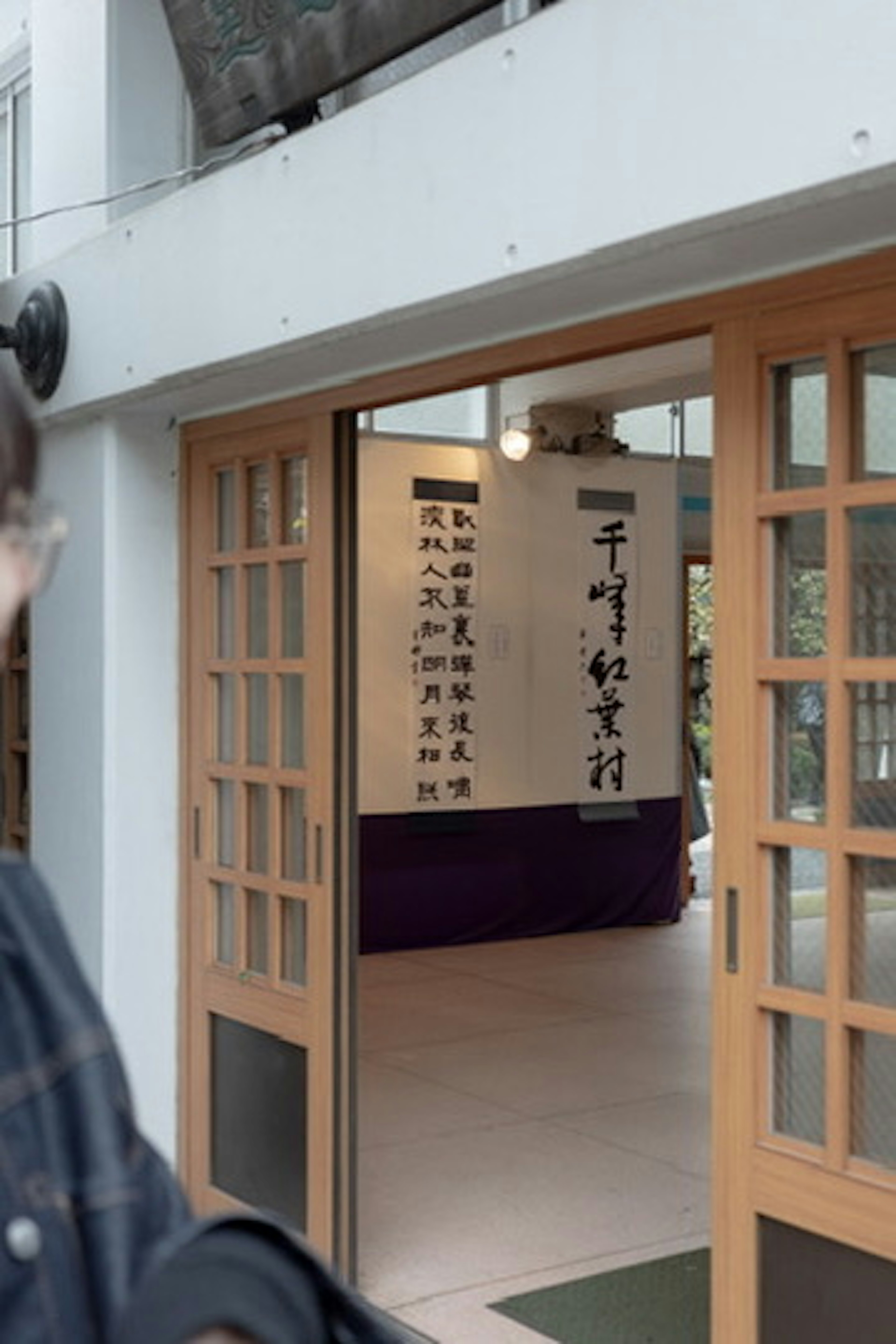 Entrance of a cultural facility with wooden doors open showcasing calligraphy artworks inside